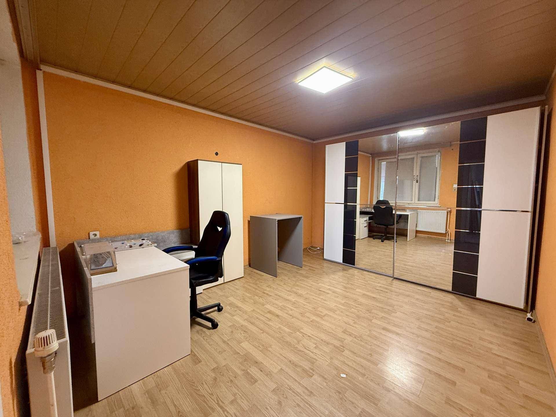 Geräumiges Schlafzimmer mit orangefarbenen Wänden, Spiegelschränken und Schreibtisch.