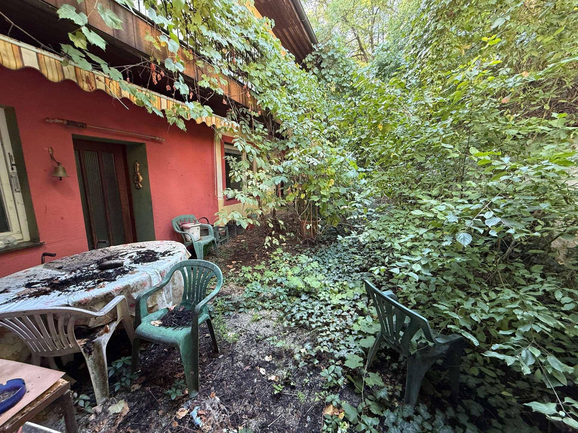 Terrasse mit Gartenmöbeln und starker Begrünung, direkter Zugang zum Garten.