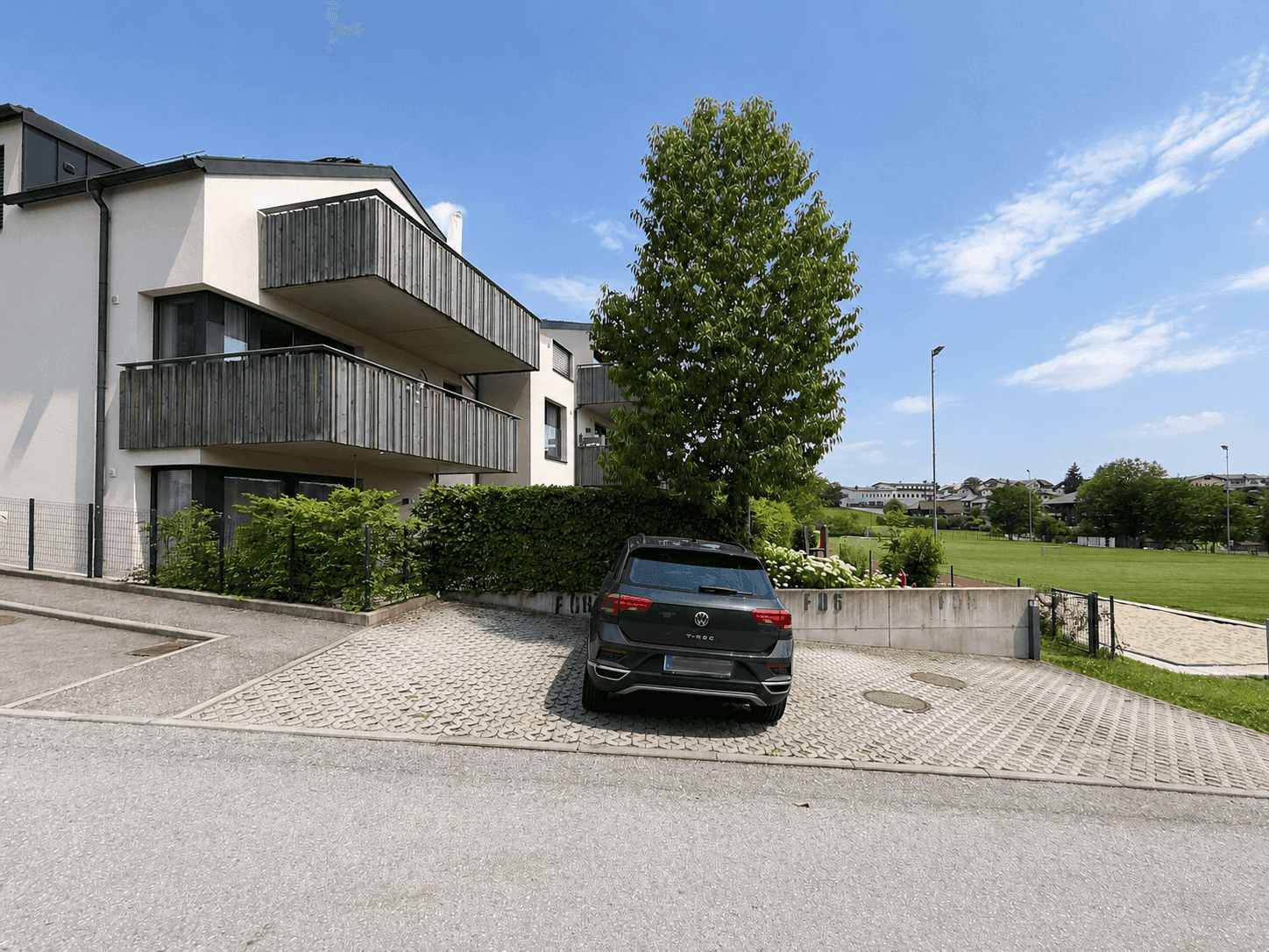 Außenansicht eines modernen Wohngebäudes mit Balkonen und Parkplatz.