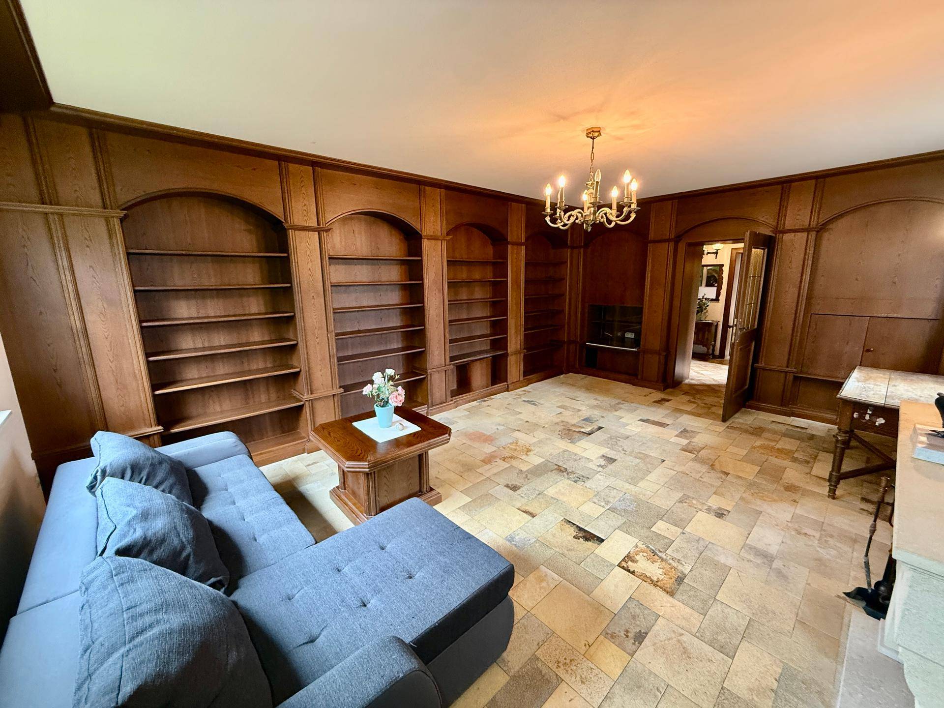 Gemütliches Wohnzimmer mit umfangreichen Holzregalen, bequemer Couch und gemustertem Fliesenboden.