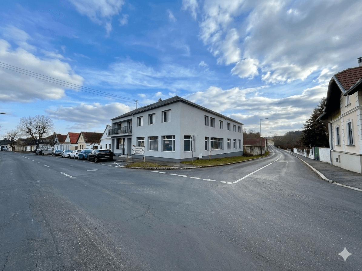 Gesamtansicht des Gebäudes an einer Straßenecke in ländlicher Umgebung unter blauem Himmel.