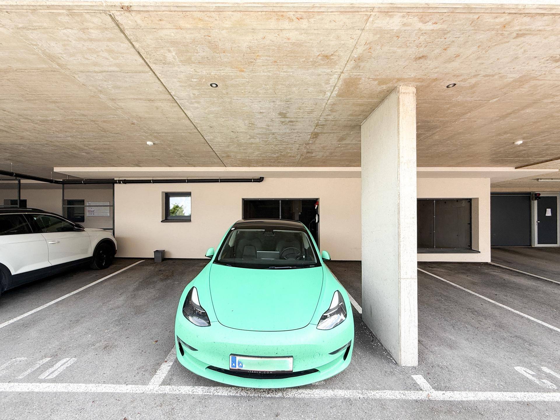 Überdachter Parkplatz mit einem Elektrofahrzeug und Betonkonstruktion.