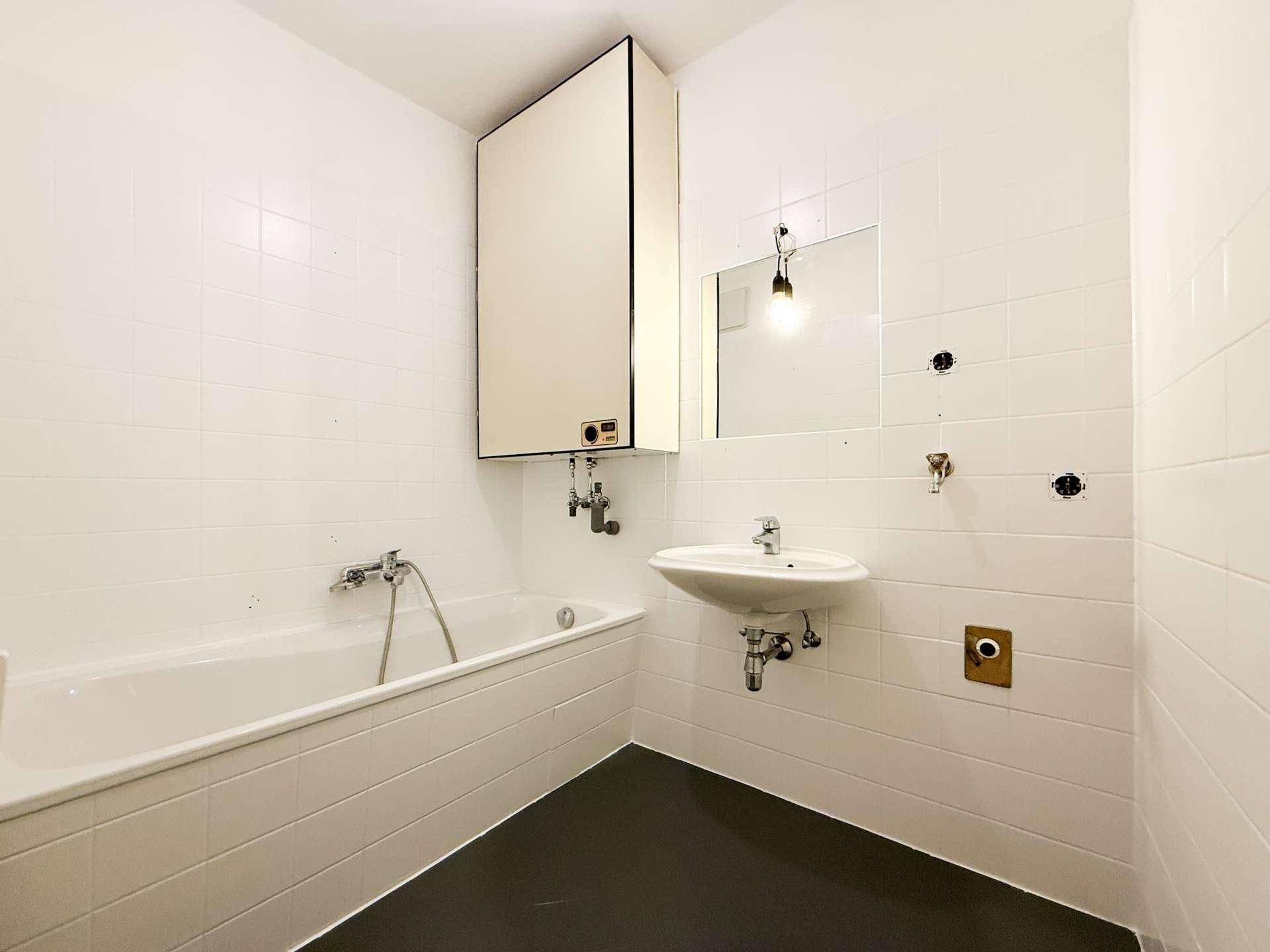 Badezimmer mit Badewanne, Waschbecken und weißen Fliesen, funktional und hell.