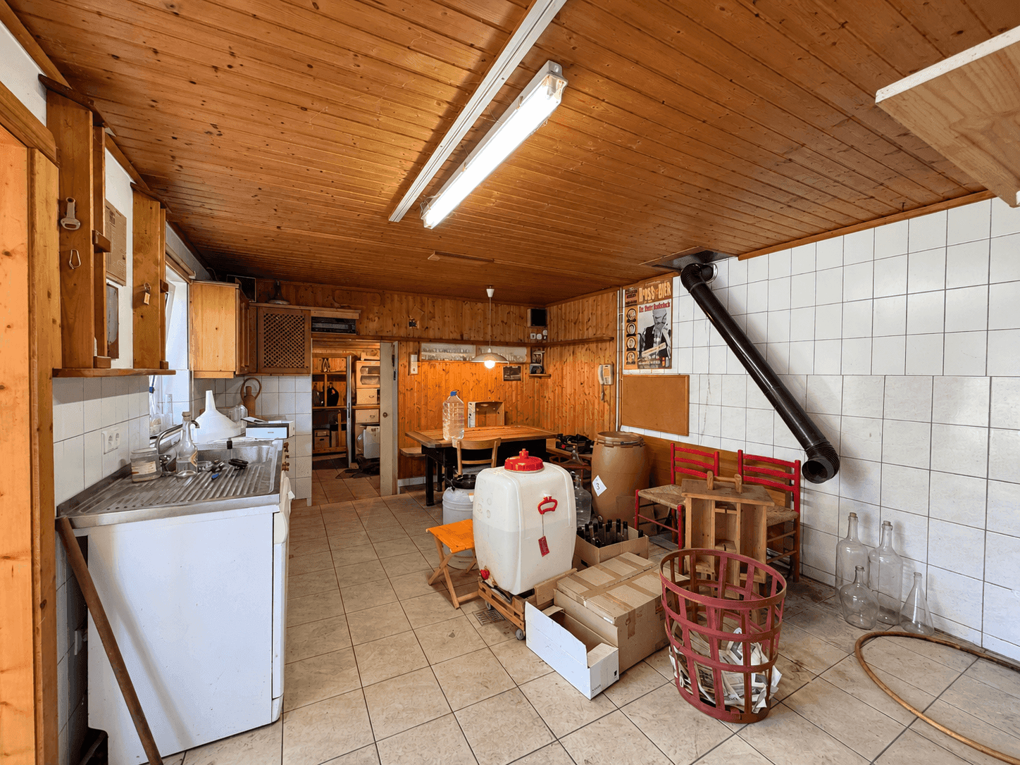 Funktionale Küche mit Fliesenboden, Holzvertäfelung und großem Arbeitsbereich.