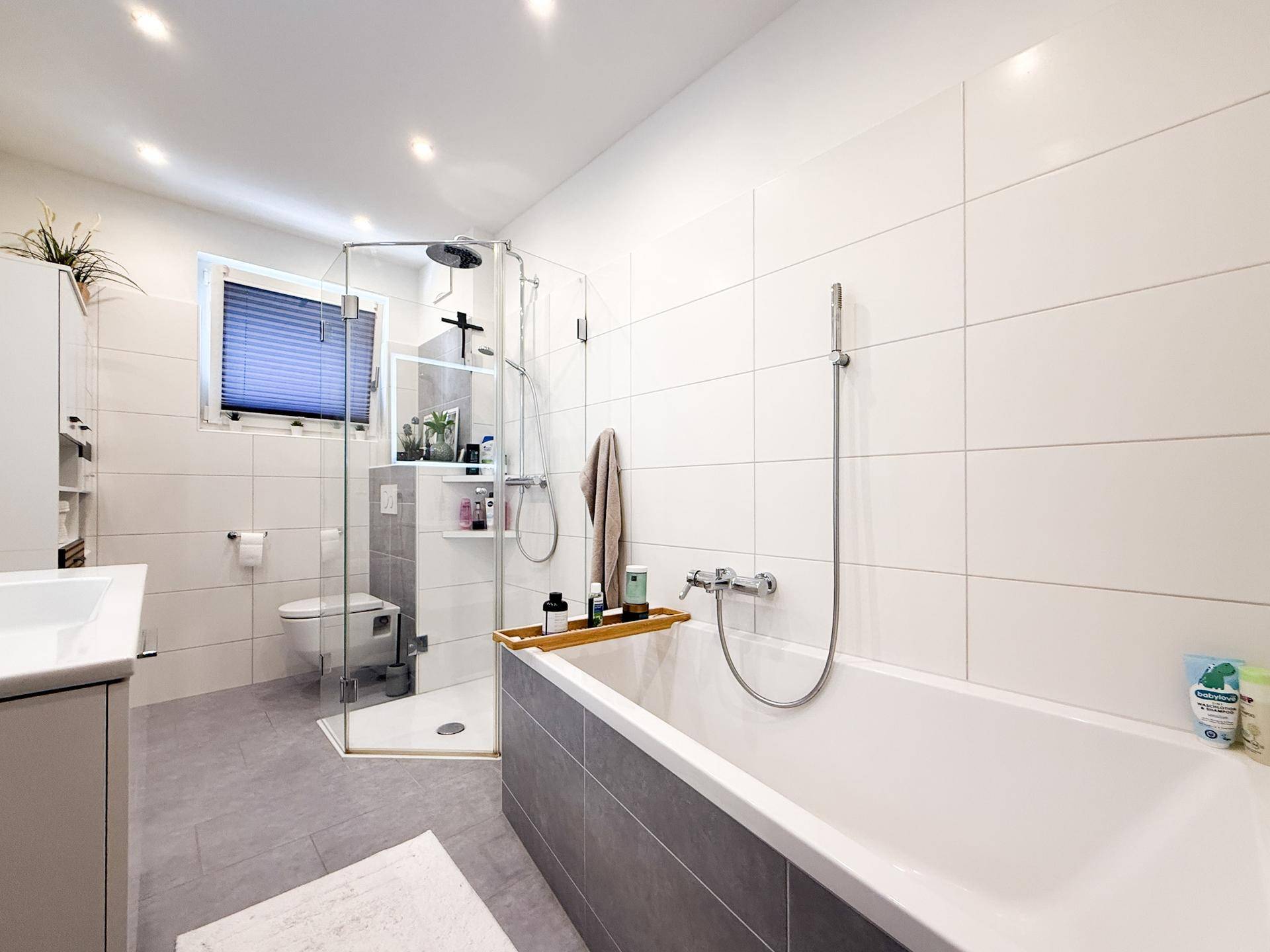 Helles Badezimmer mit Badewanne, separater Dusche und modernen Fliesen.