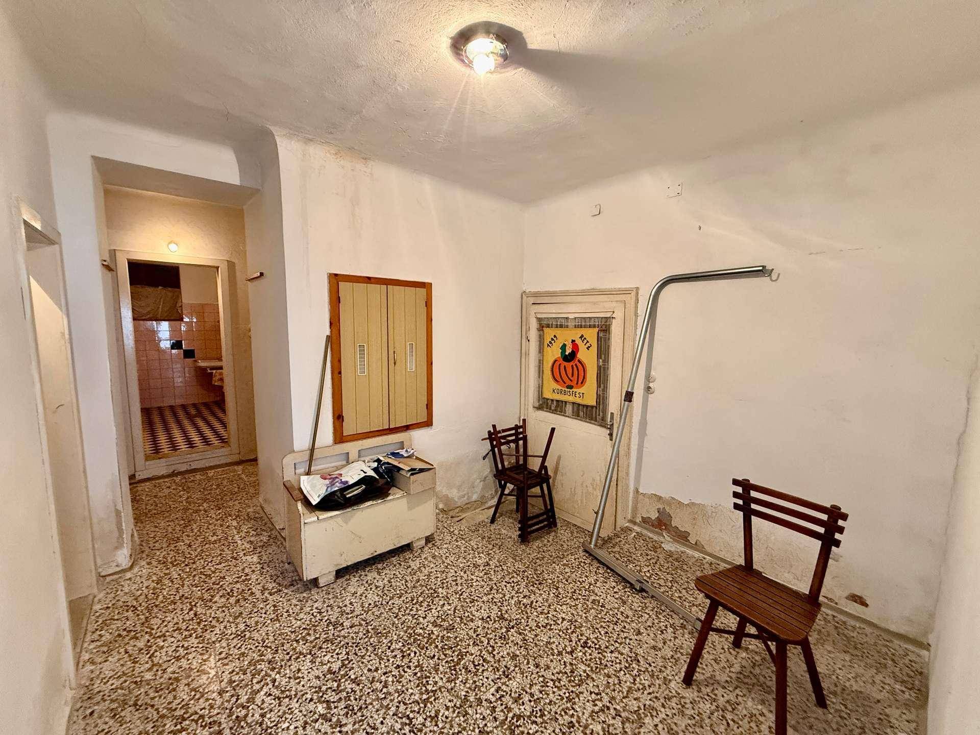 Flur mit gemustertem Terrazzoboden und Zugang zu weiteren Räumen, inklusive Badezimmer.