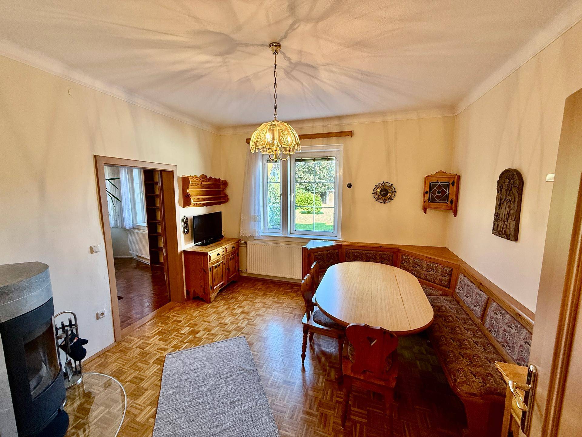 Esszimmer mit Holzboden, traditioneller Eckbank und Kaminofen für gemütliche Abende.