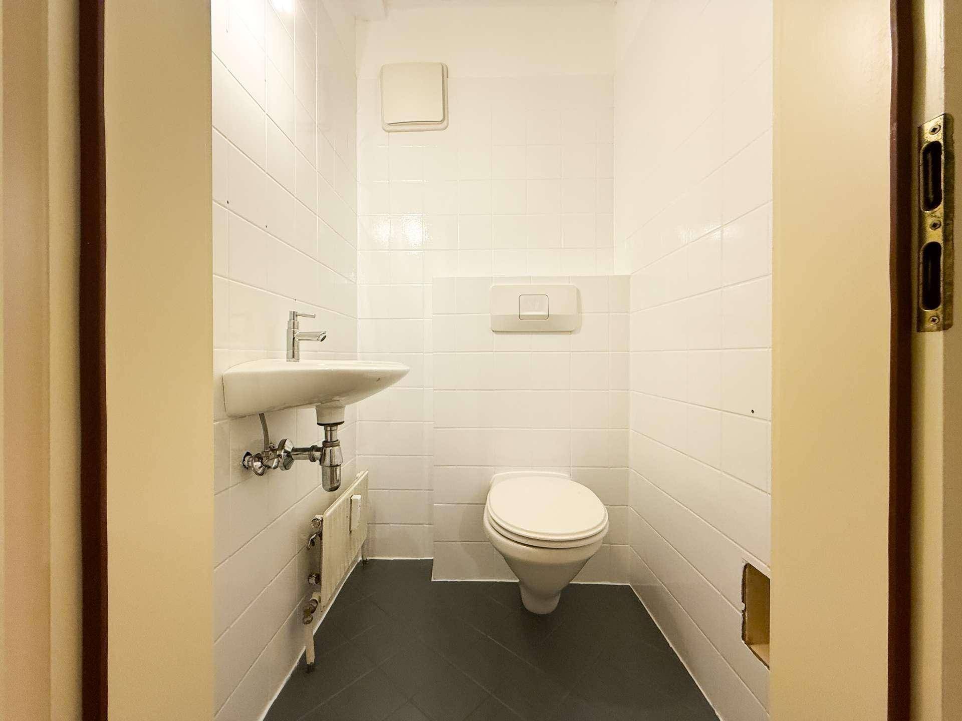 Separates WC mit Waschbecken und weißen Fliesen, praktisch und sauber.
