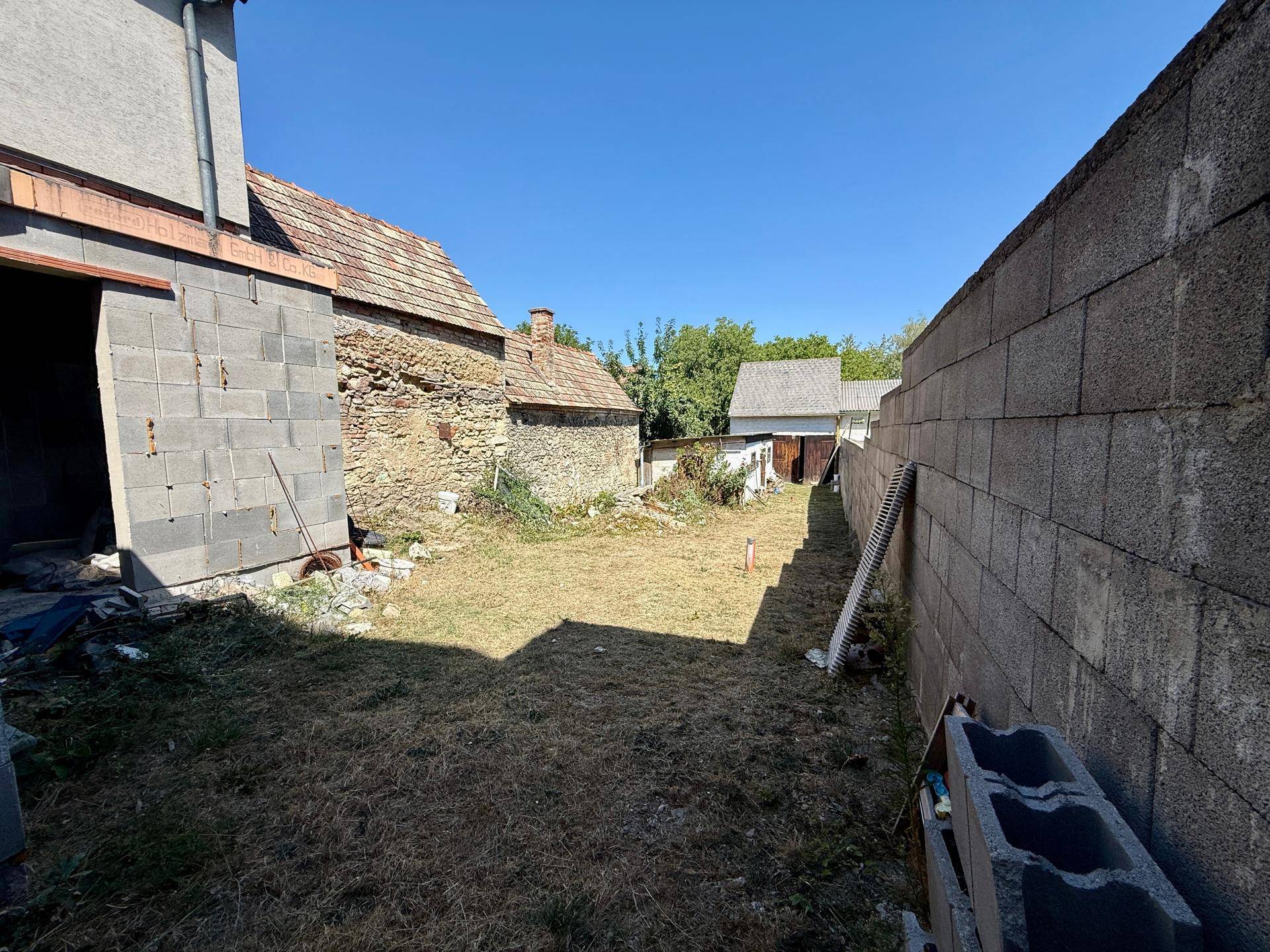 Hinterhofbereich mit einer Mischung aus alten Gebäuden und Neubau, umgeben von einer Betonmauer.