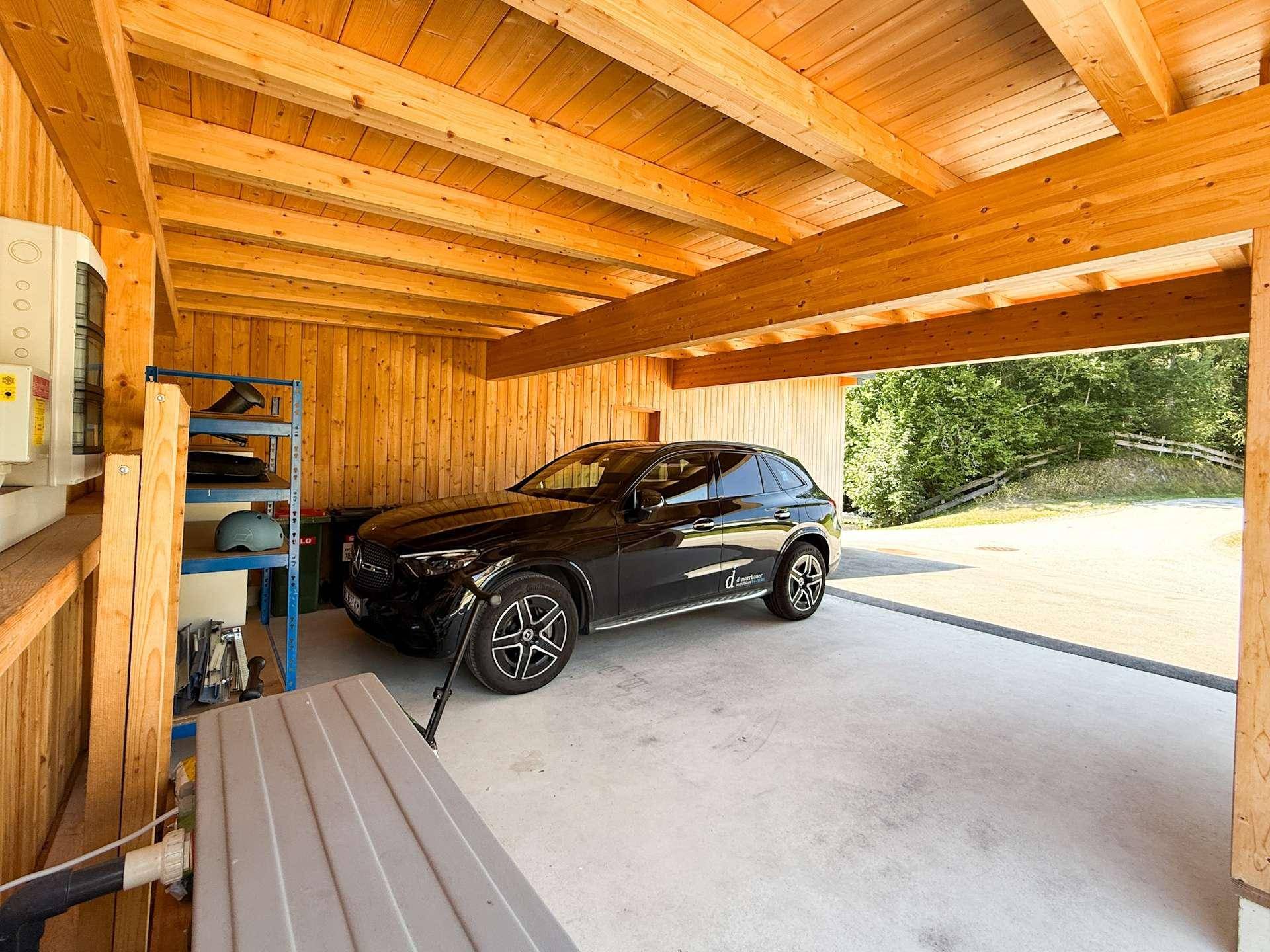 Geräumiger Holz-Carport mit Betonboden und Platz für ein Fahrzeug.
