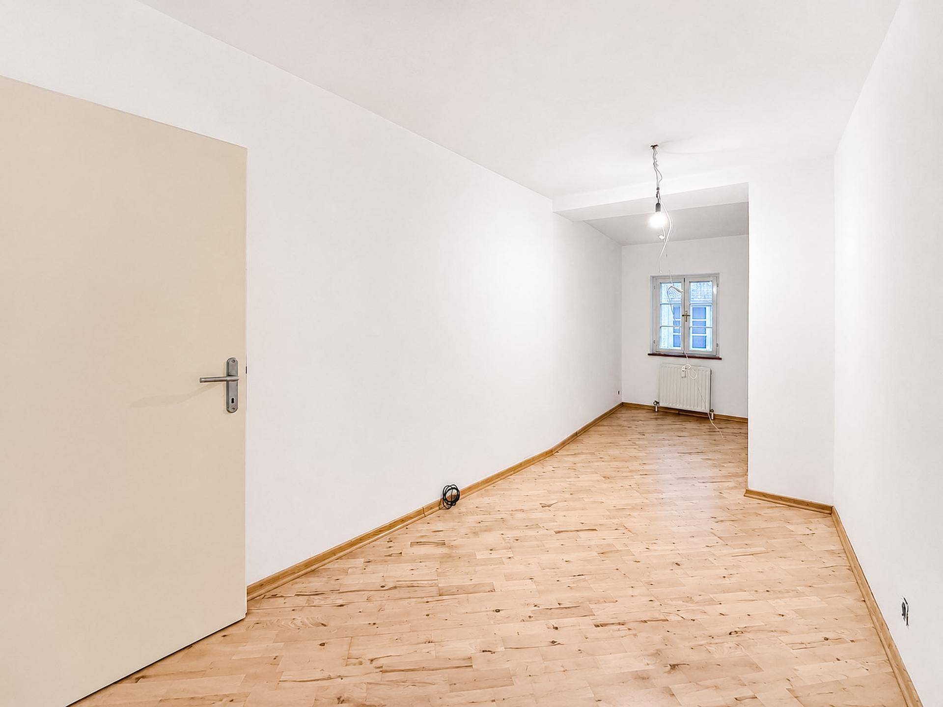 Ruhiges Zimmer mit Holzboden und Fenster, ideal als Schlaf- oder Arbeitszimmer.