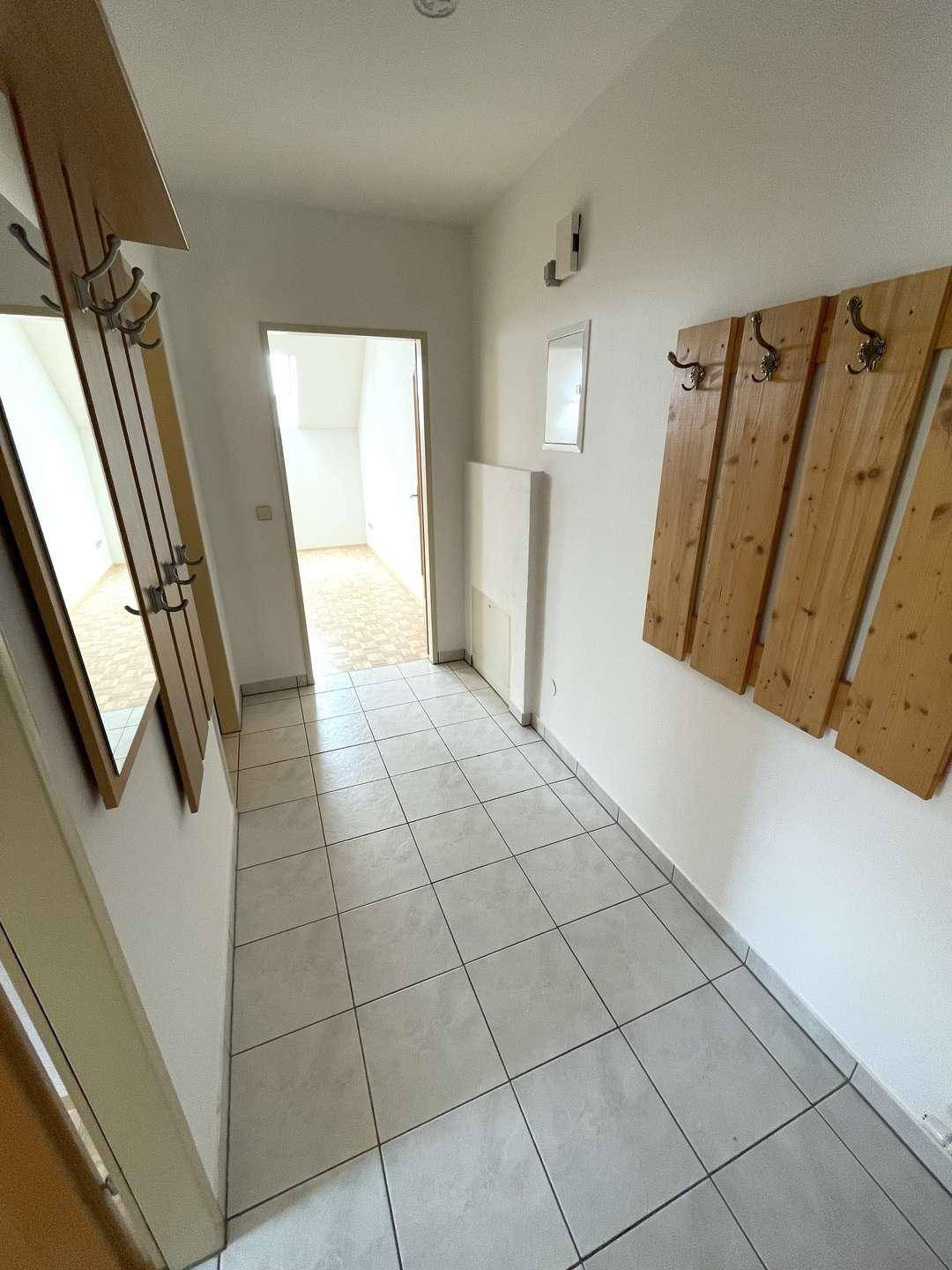Heller Flur mit Fliesenboden und Garderobe, führt zu weiteren Räumen.