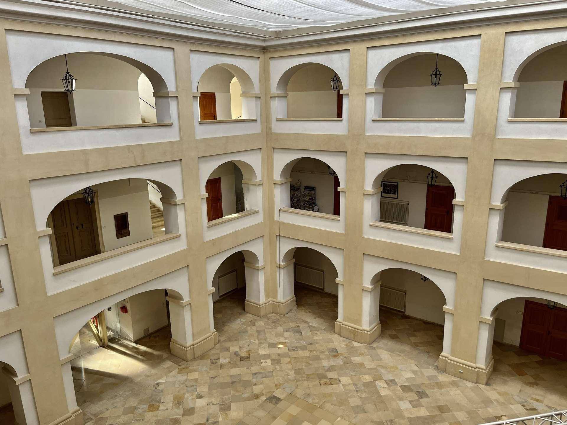 Historischer Innenhof mit mehreren Arkaden und einem gemusterten Steinboden, überdacht mit Stoff.