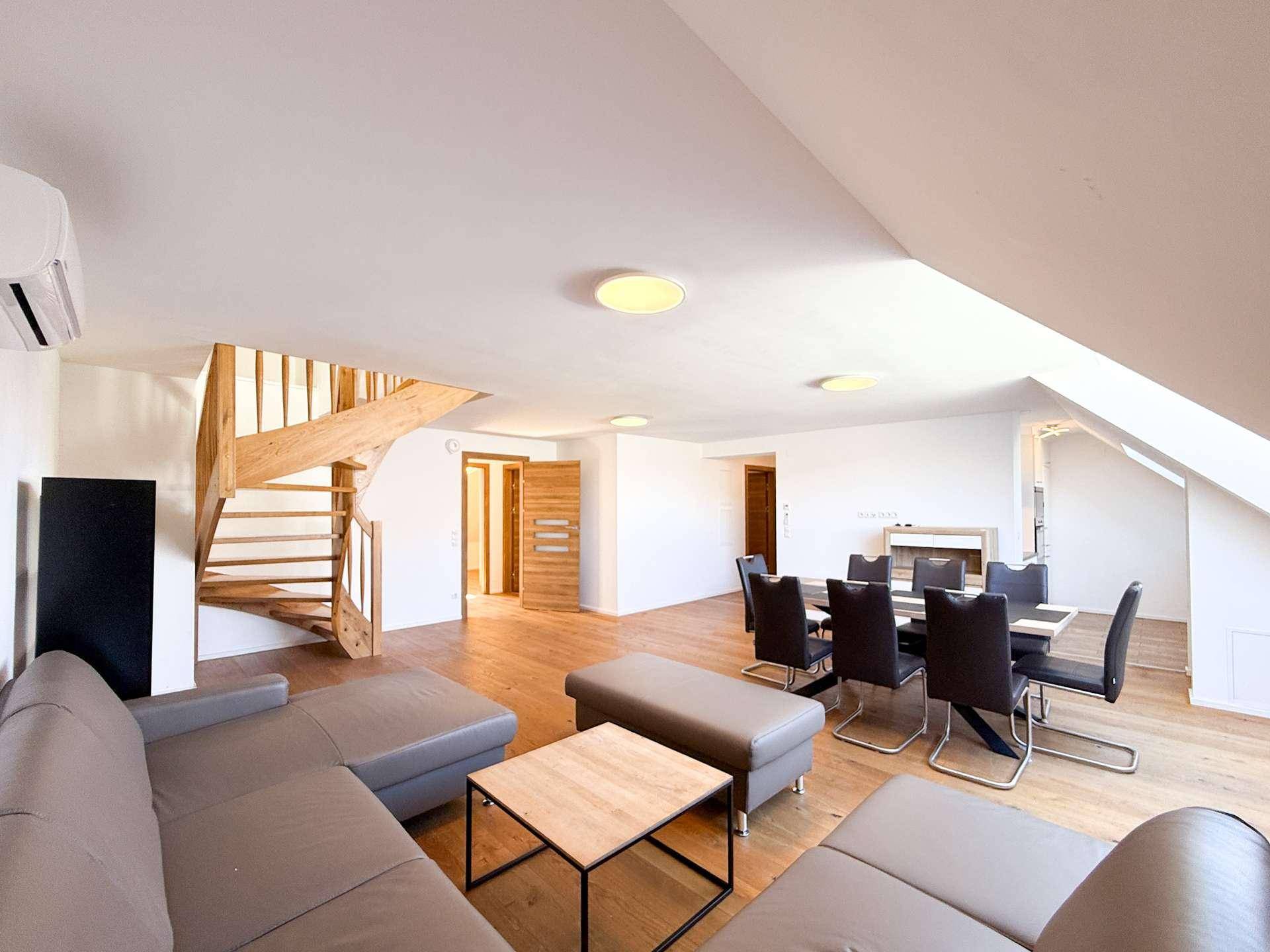 Gemütlicher Wohnbereich mit Sofa, Couchtisch und einer eleganten Holztreppe, die in die obere Etage führt.