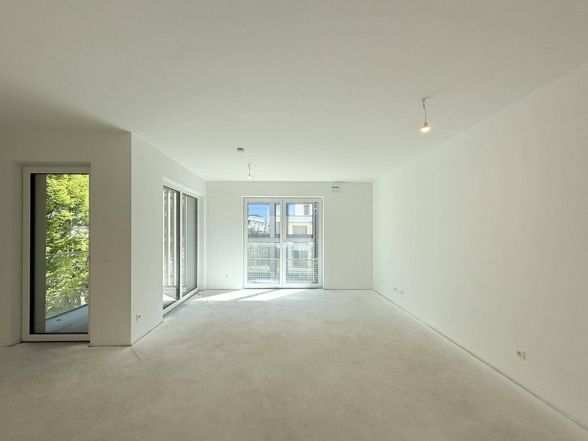 Heller, unmöblierter Raum im Neubau mit mehreren Fensterfronten für viel Licht.