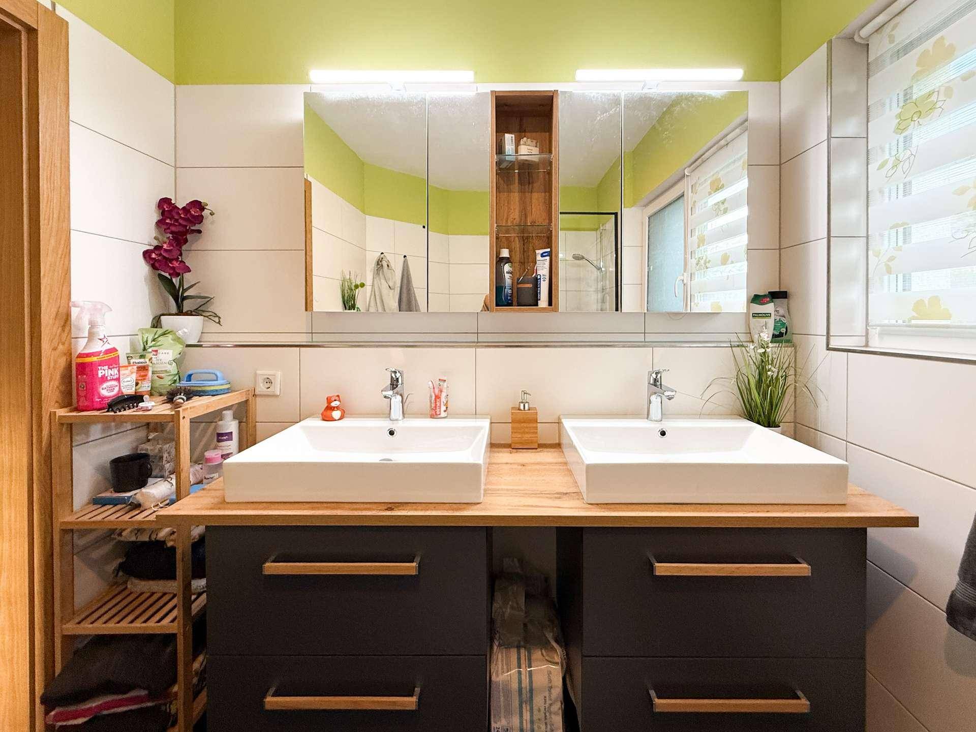 Doppelwaschbecken mit Holzplatte und Spiegelschrank in einem modernen Badezimmer.