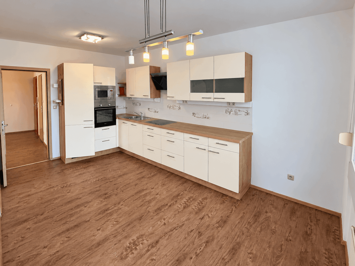 Moderne Einbauküche mit hellen Fronten, Holz-Arbeitsplatte und integrierten Geräten für effizientes Kochen.