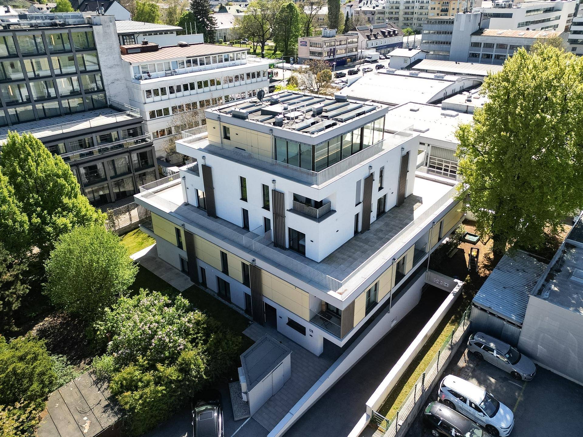 Moderne Wohnanlage mit Flachdach, Balkonen und Photovoltaikanlage aus der Vogelperspektive.