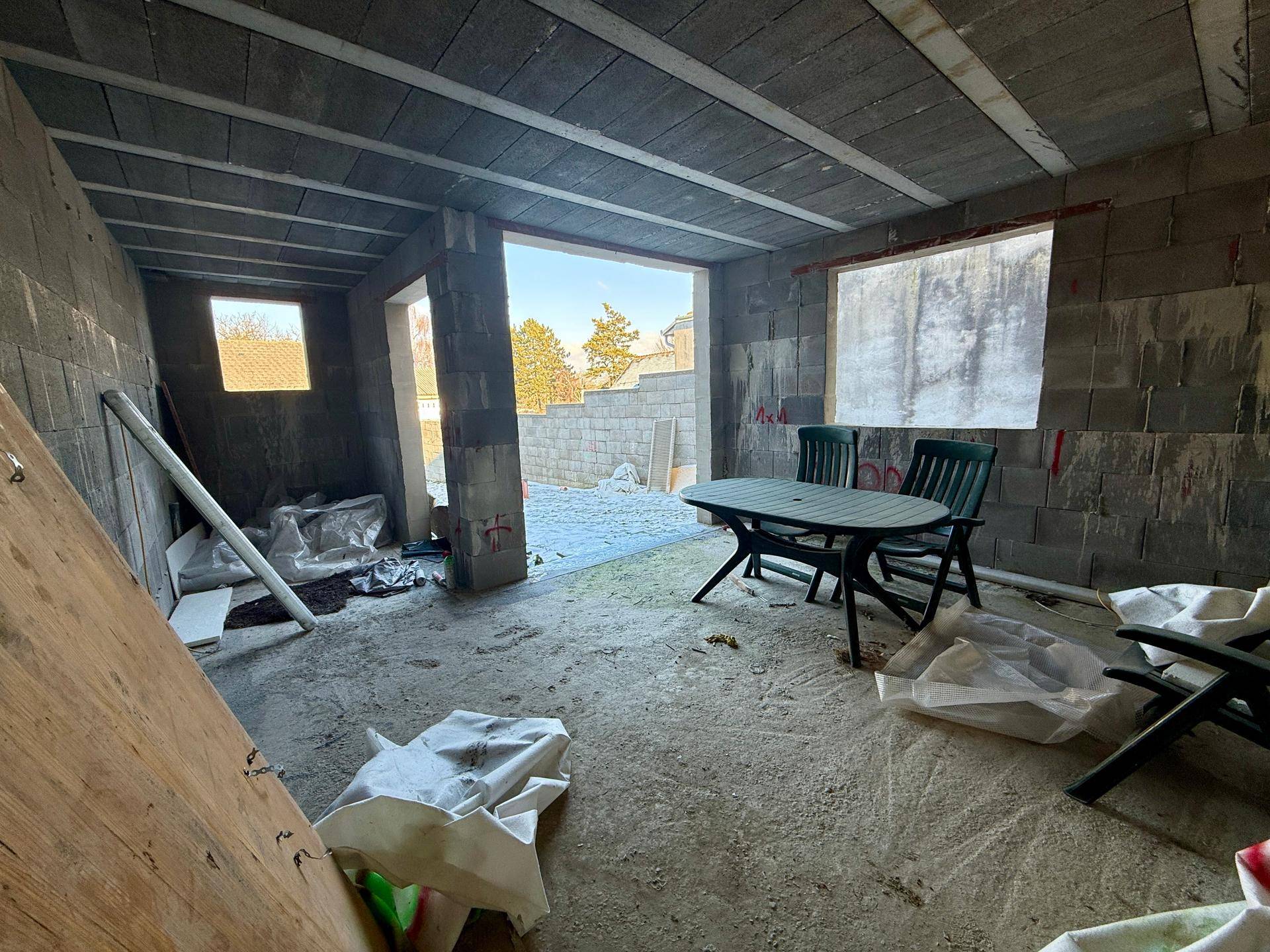Rohbau-Innenraum mit Betonwänden und provisorischen Möbeln, bietet Ausbaupotenzial.