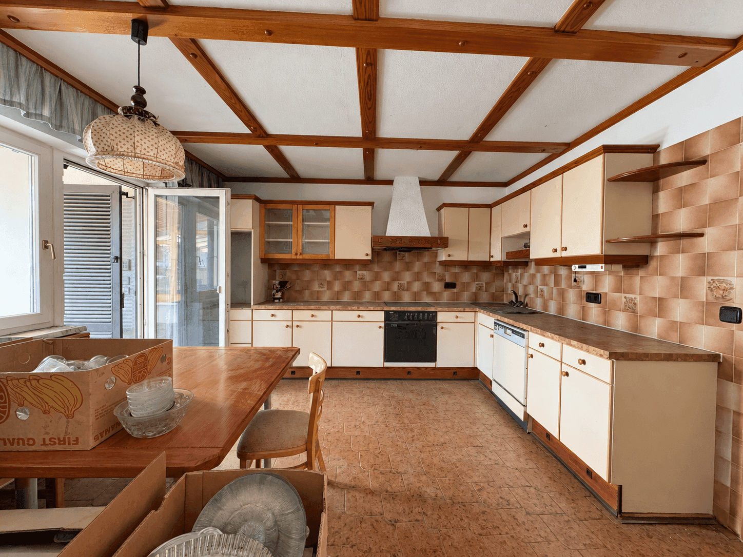 Geräumige Küche mit Einbauschränken, Fliesenboden und Zugang zur Terrasse.
