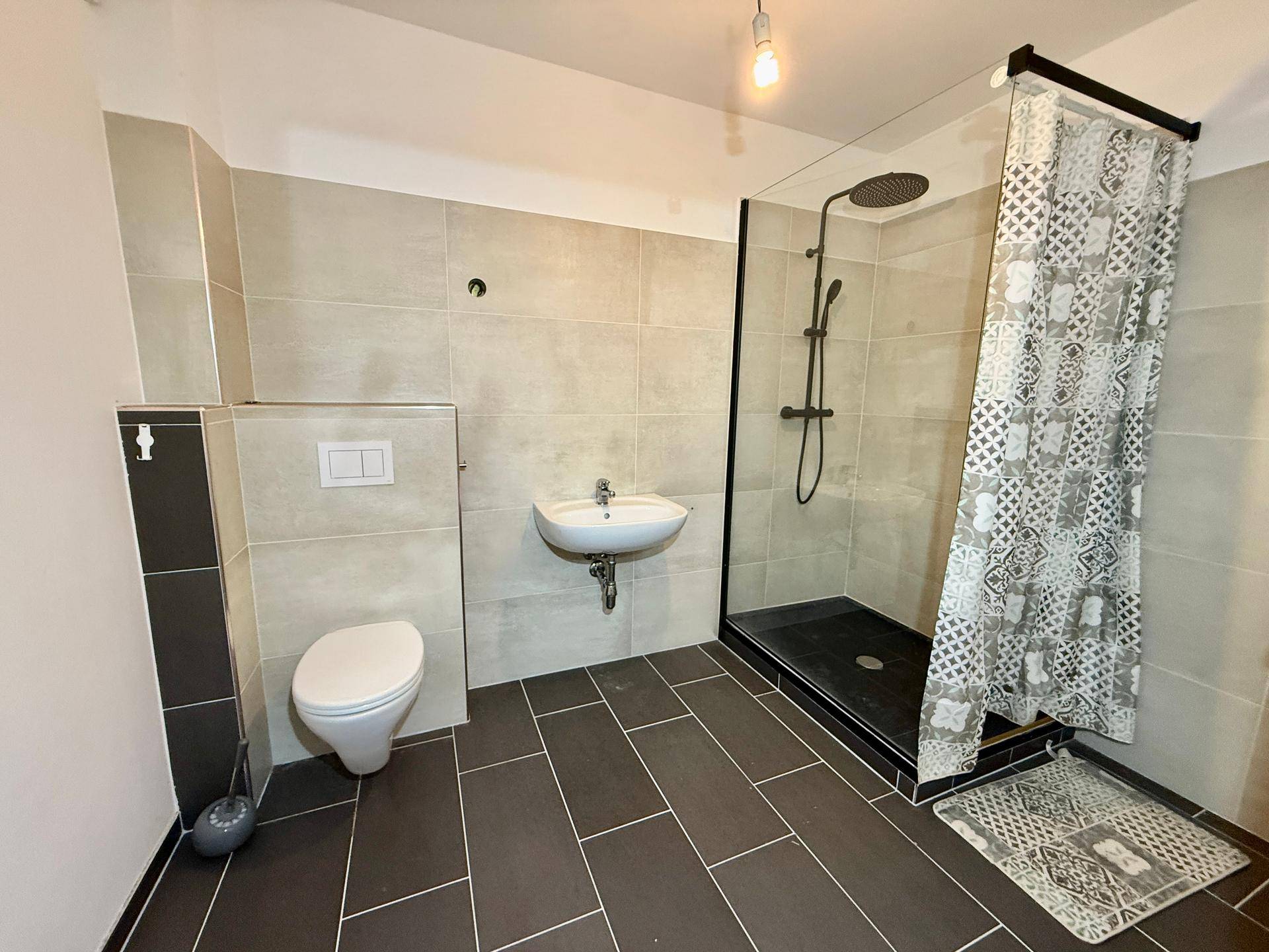 Zeitgemäßes Badezimmer mit ebenerdiger Dusche, Waschbecken und Wand-WC.