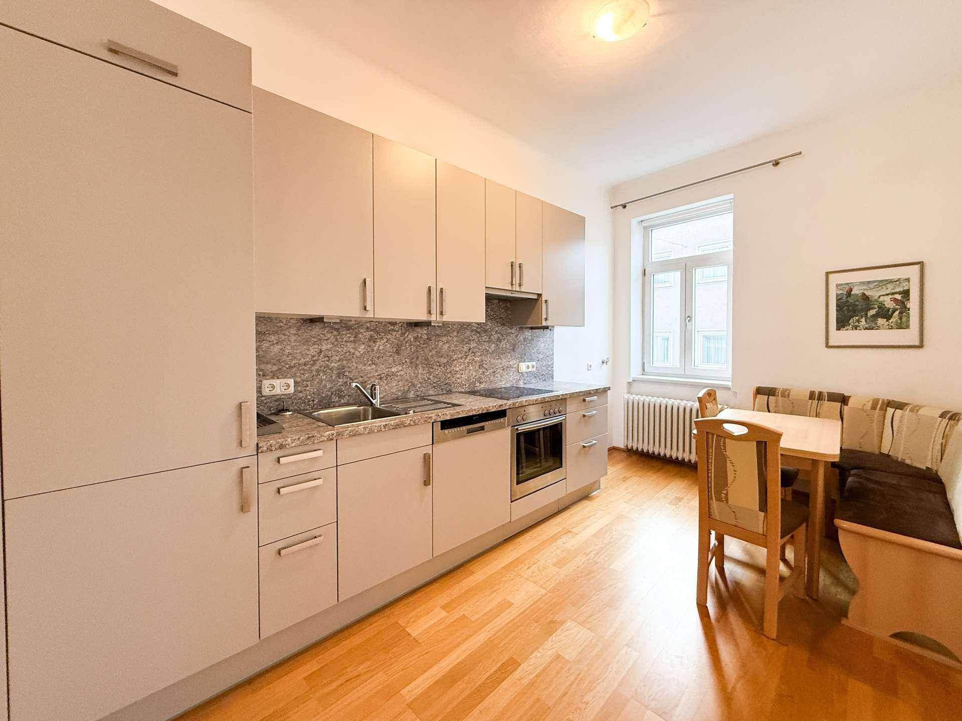 Moderne Einbauküche mit Essbereich, ausgestattet mit hellen Schränken und integrierten Geräten.