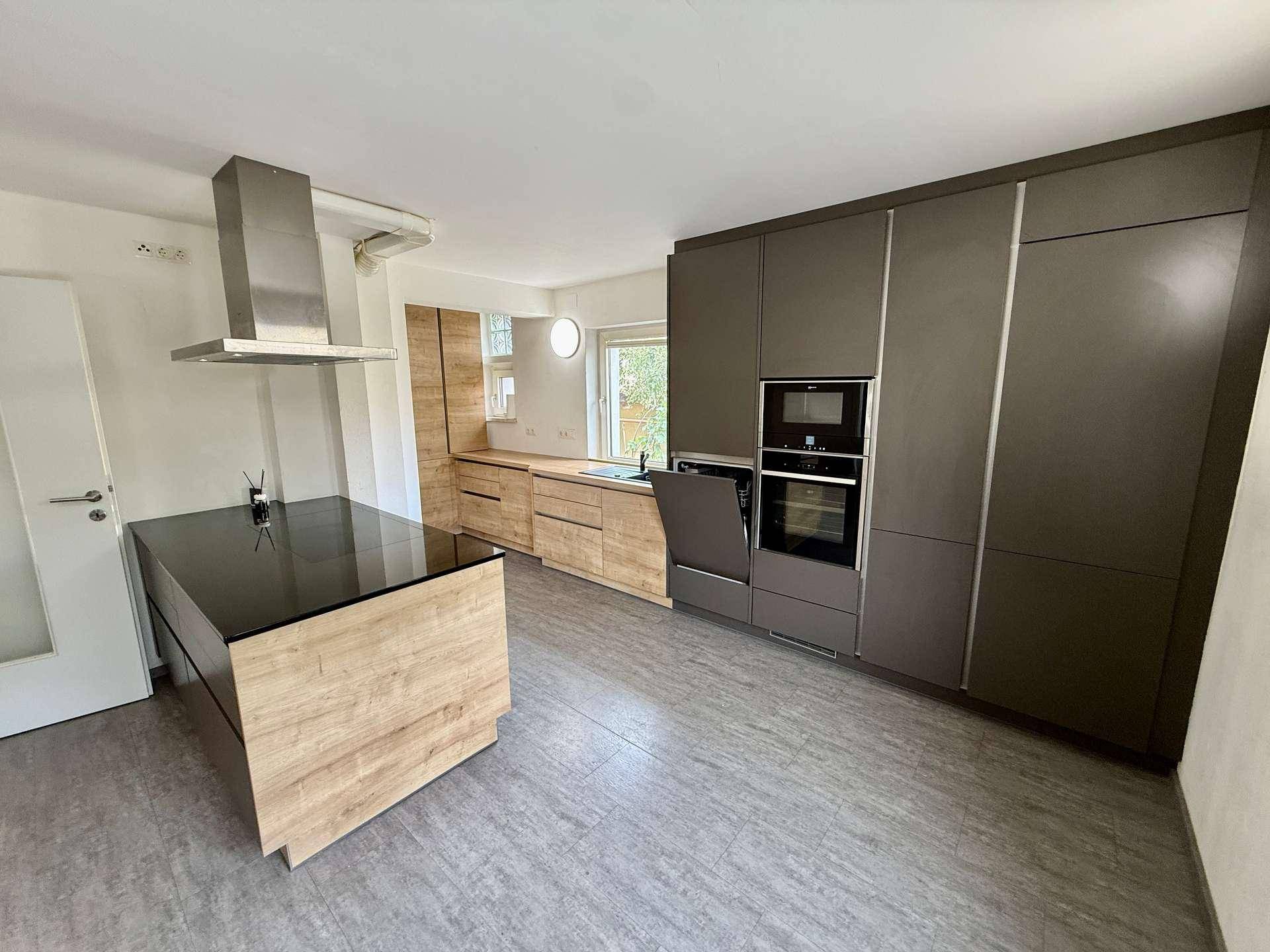Detailansicht der modernen Küche mit Kücheninsel, integrierten Geräten und Holzdetails.