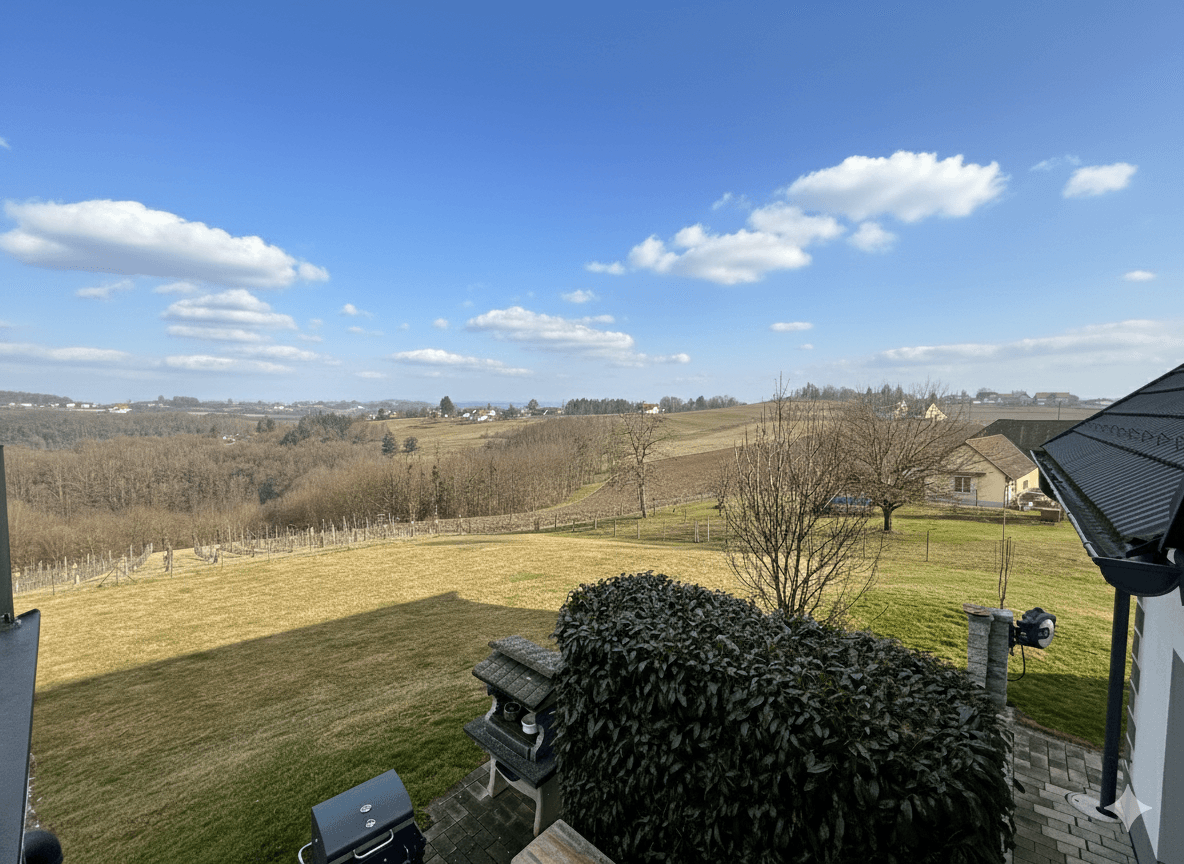 Weitläufiger Blick über die grüne Landschaft mit Weinbergen und bewaldeten Hügeln.