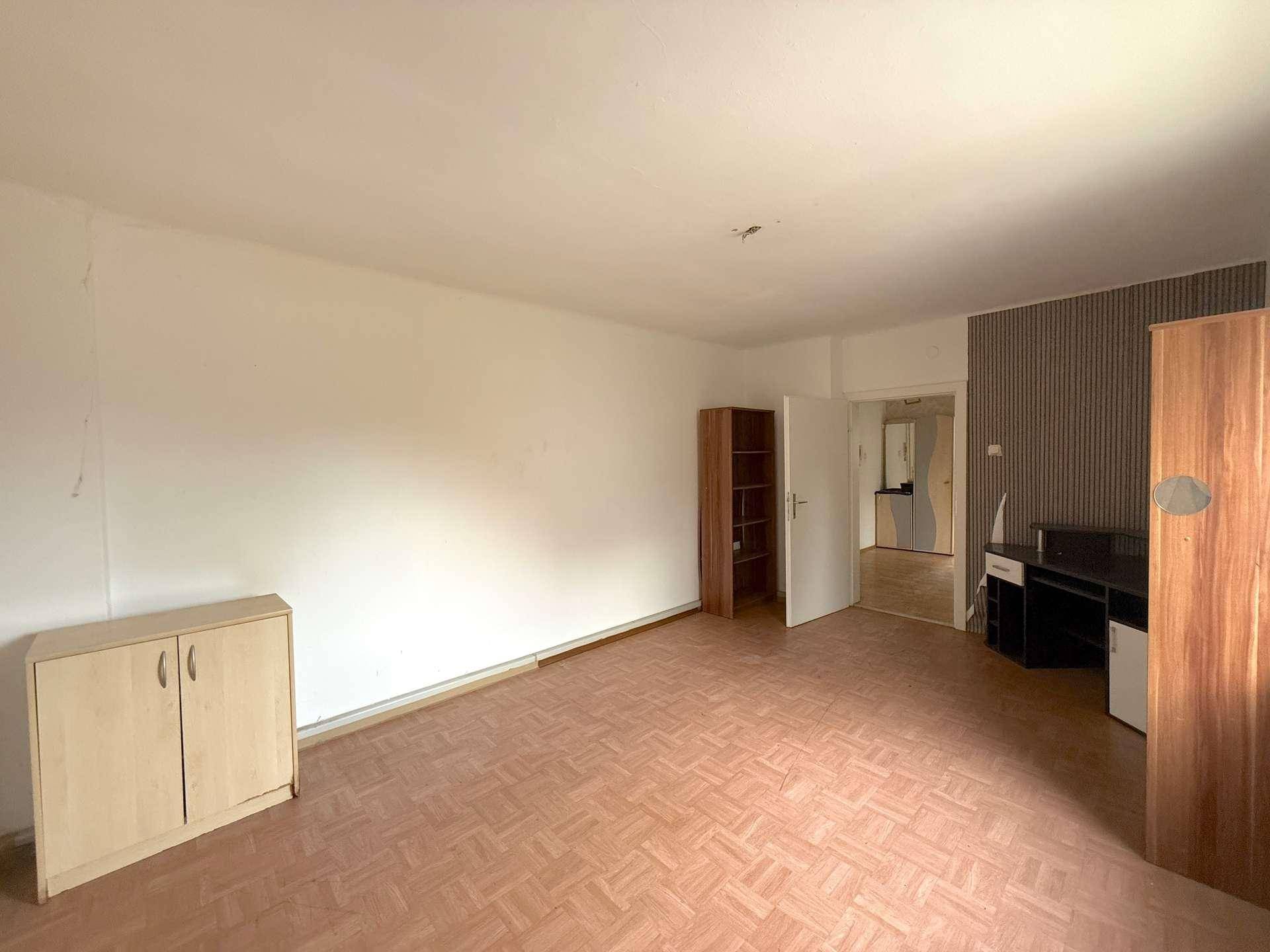 Schlafzimmer mit Laminatboden, Schrank und Blick in den Flur.