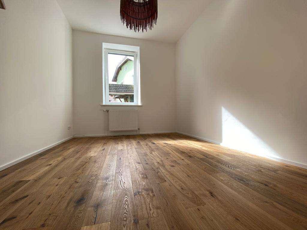 Freundliches Zimmer mit Holzboden und einem Fenster, das einen Blick nach draußen bietet.