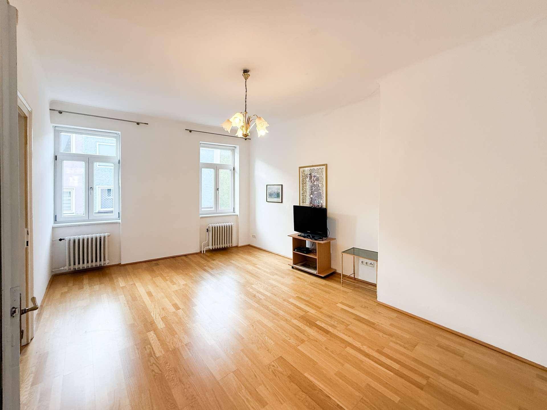 Lichtdurchfluteter Wohnbereich mit Parkettboden und zwei Fenstern, bietet viel Platz für Ihre Einrichtungsideen.