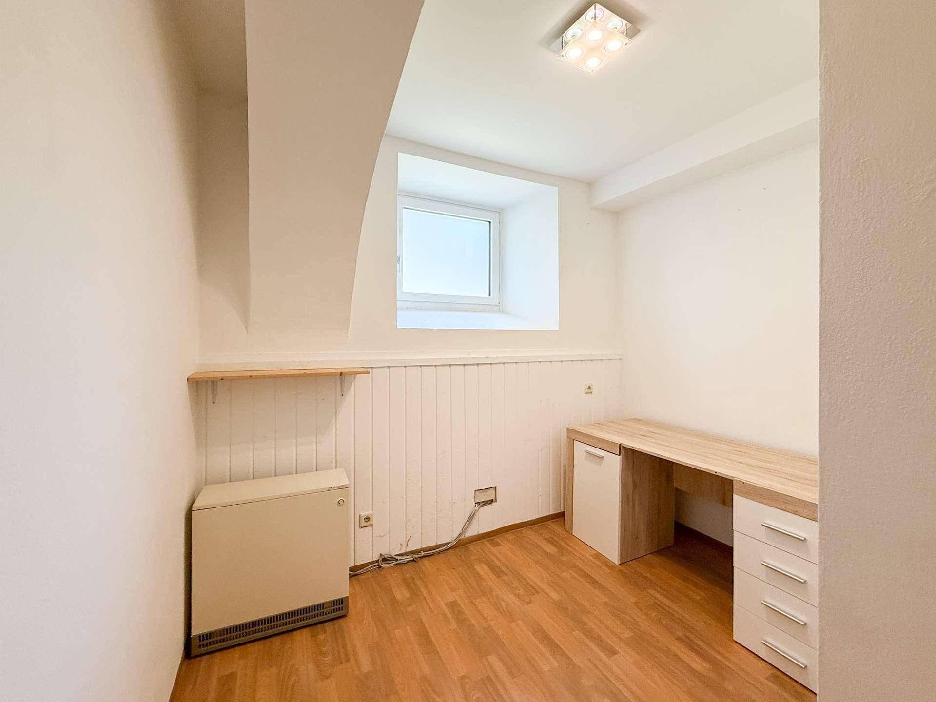 Kleines Büro mit Schreibtisch, Regal und Fenster für eine angenehme Arbeitsumgebung.