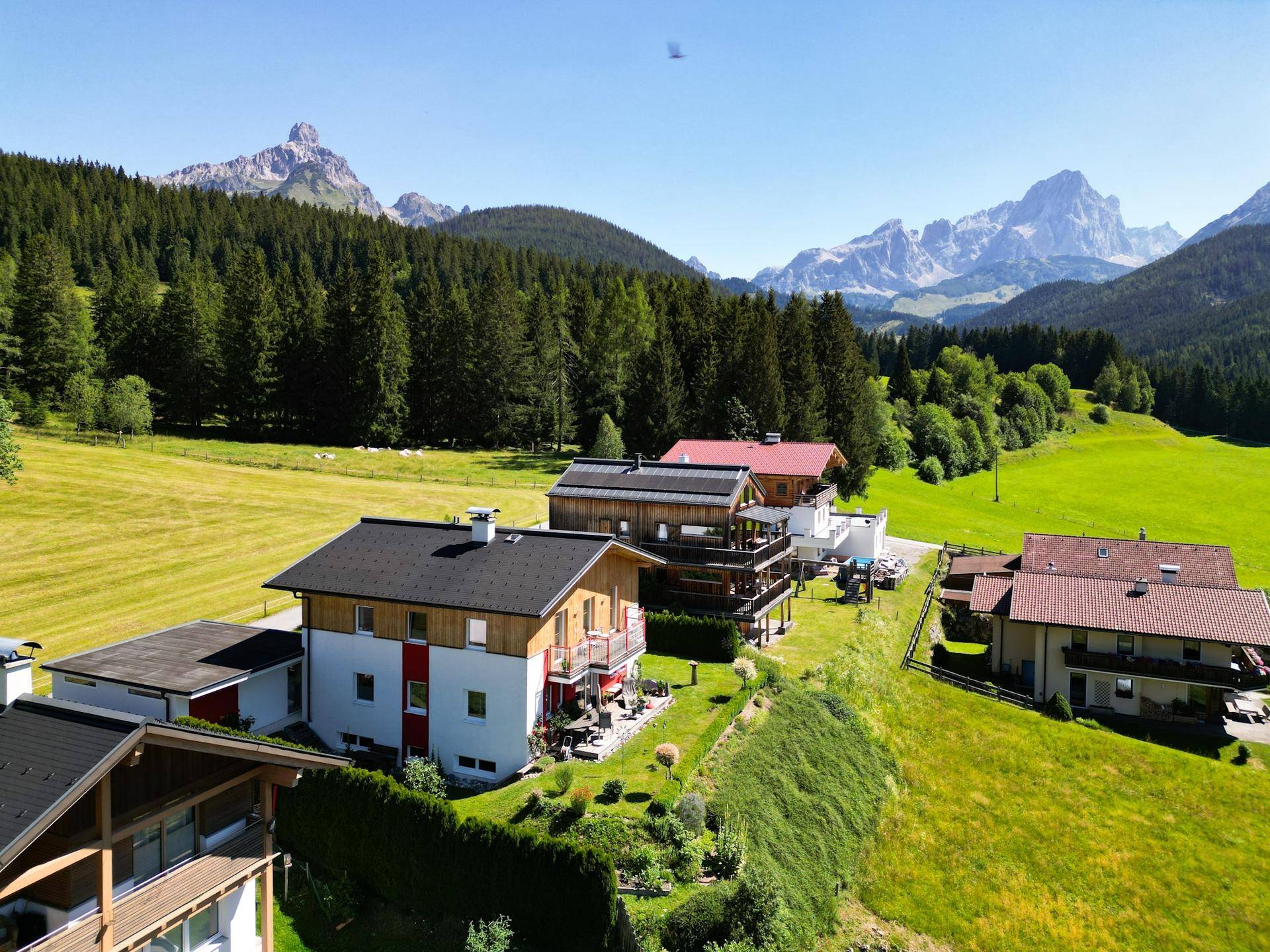 Luftaufnahme des Anwesens mit mehreren Gebäuden, umgeben von grünen Wiesen und Bergen.