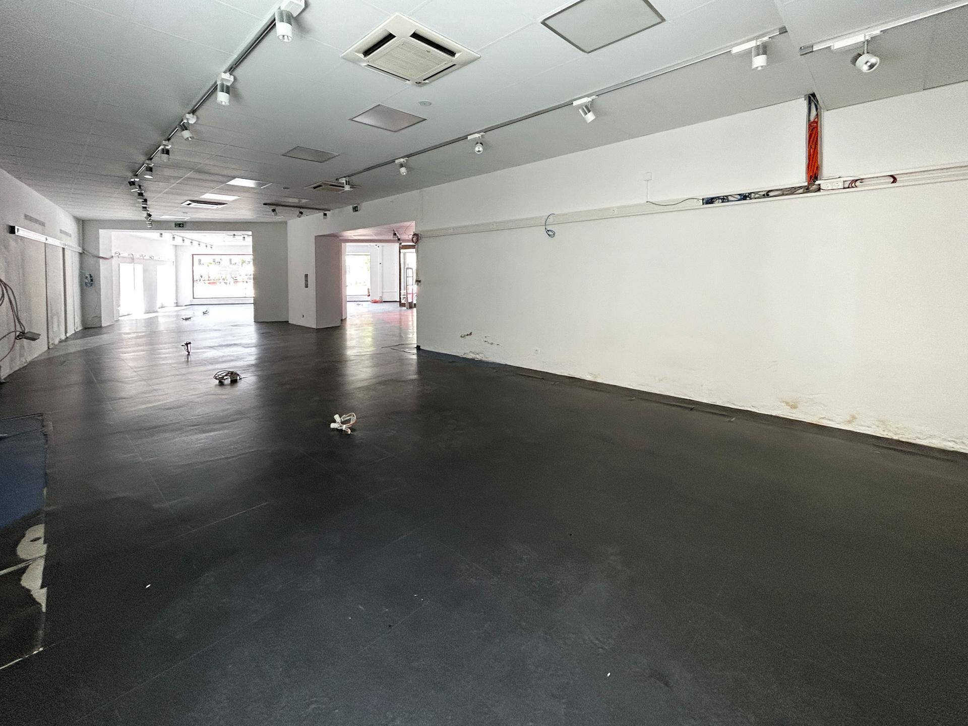 Großer, leerer Gewerberaum mit hohen Decken und sichtbaren Installationen, bereit für den Ausbau.