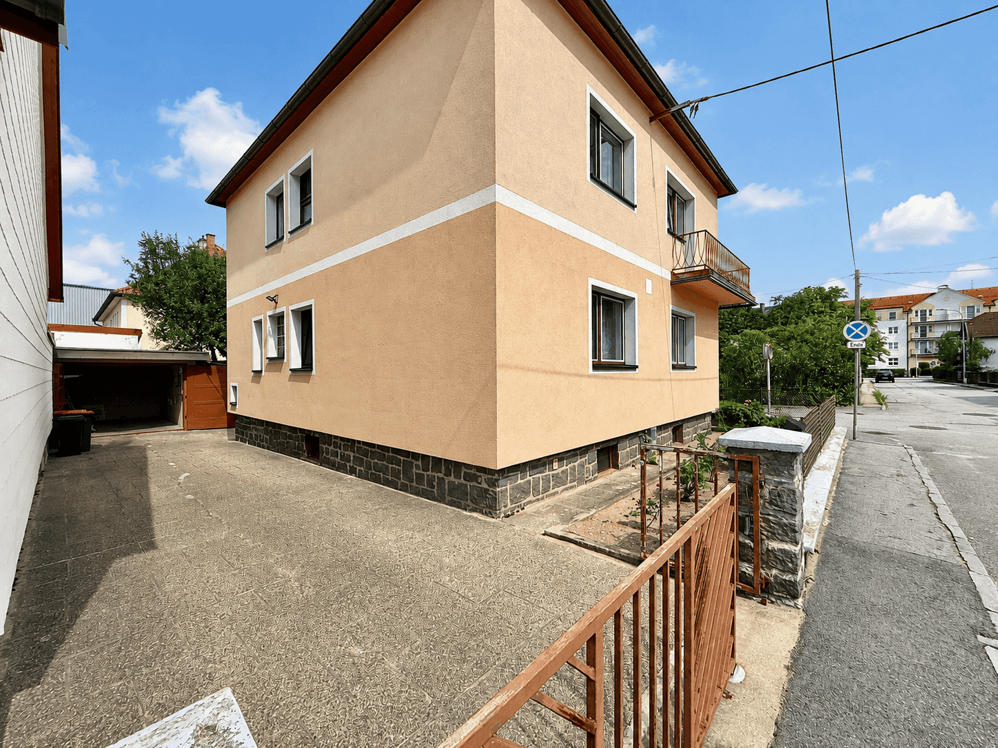 Seitenansicht des Hauses mit gepflasterter Einfahrt und Zugang zur Garage.