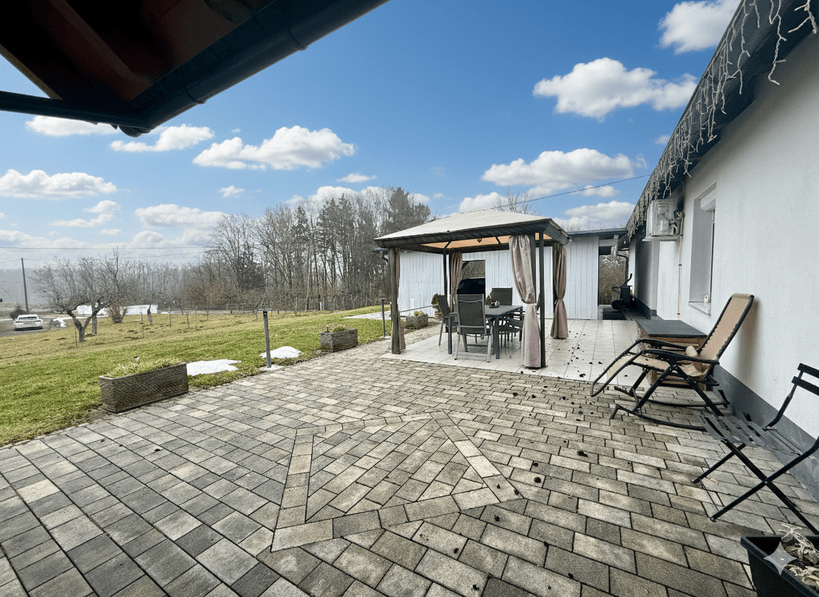 Gepflasterte Terrasse mit Gartenpavillon und Sitzgelegenheiten, die einen weiten Blick auf die Landschaft bietet.