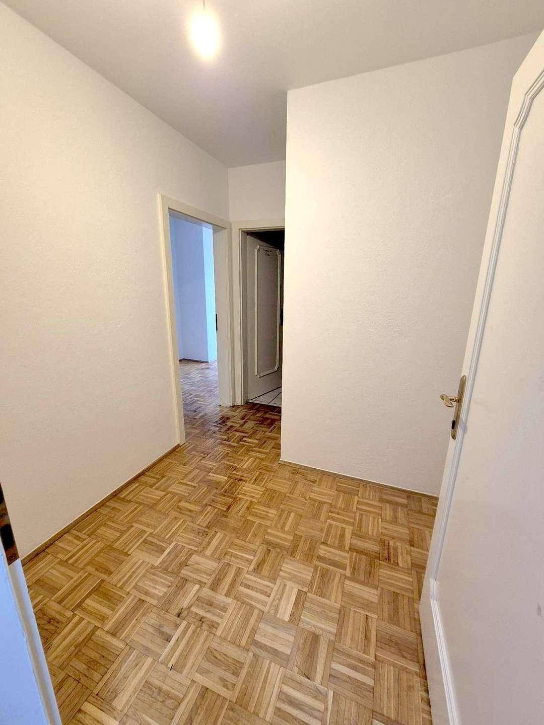 Heller Flur mit Parkettboden und Zugang zu weiteren Räumen, funktional und einladend.