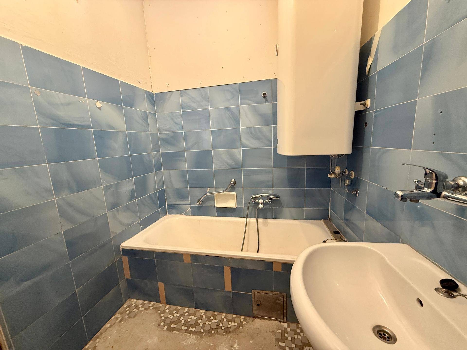 Badezimmer mit blauen Fliesen, Badewanne und Bidet, in originalem Zustand.