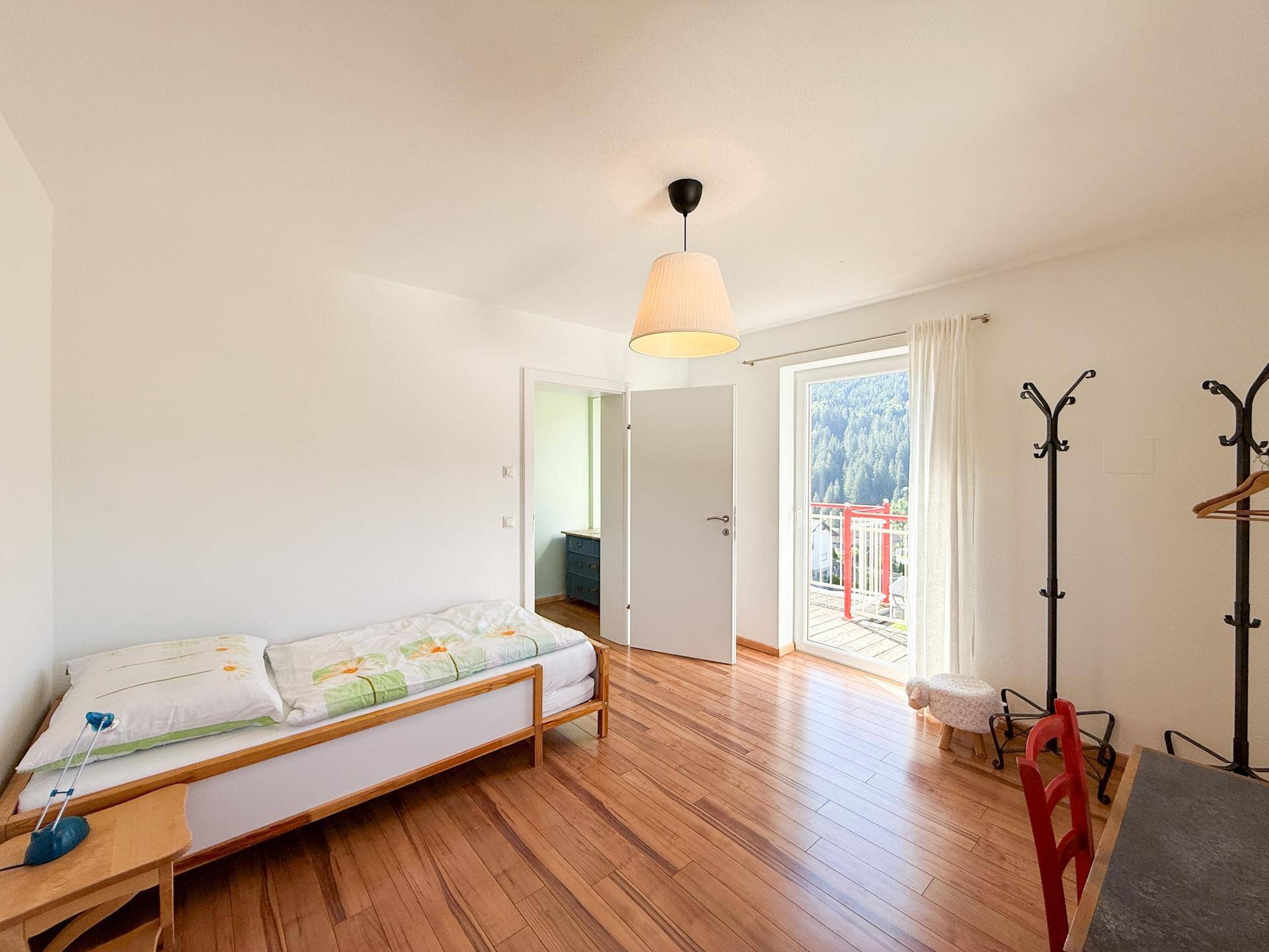 Helles Schlafzimmer mit Holzboden und Zugang zu einem Balkon mit Bergblick.