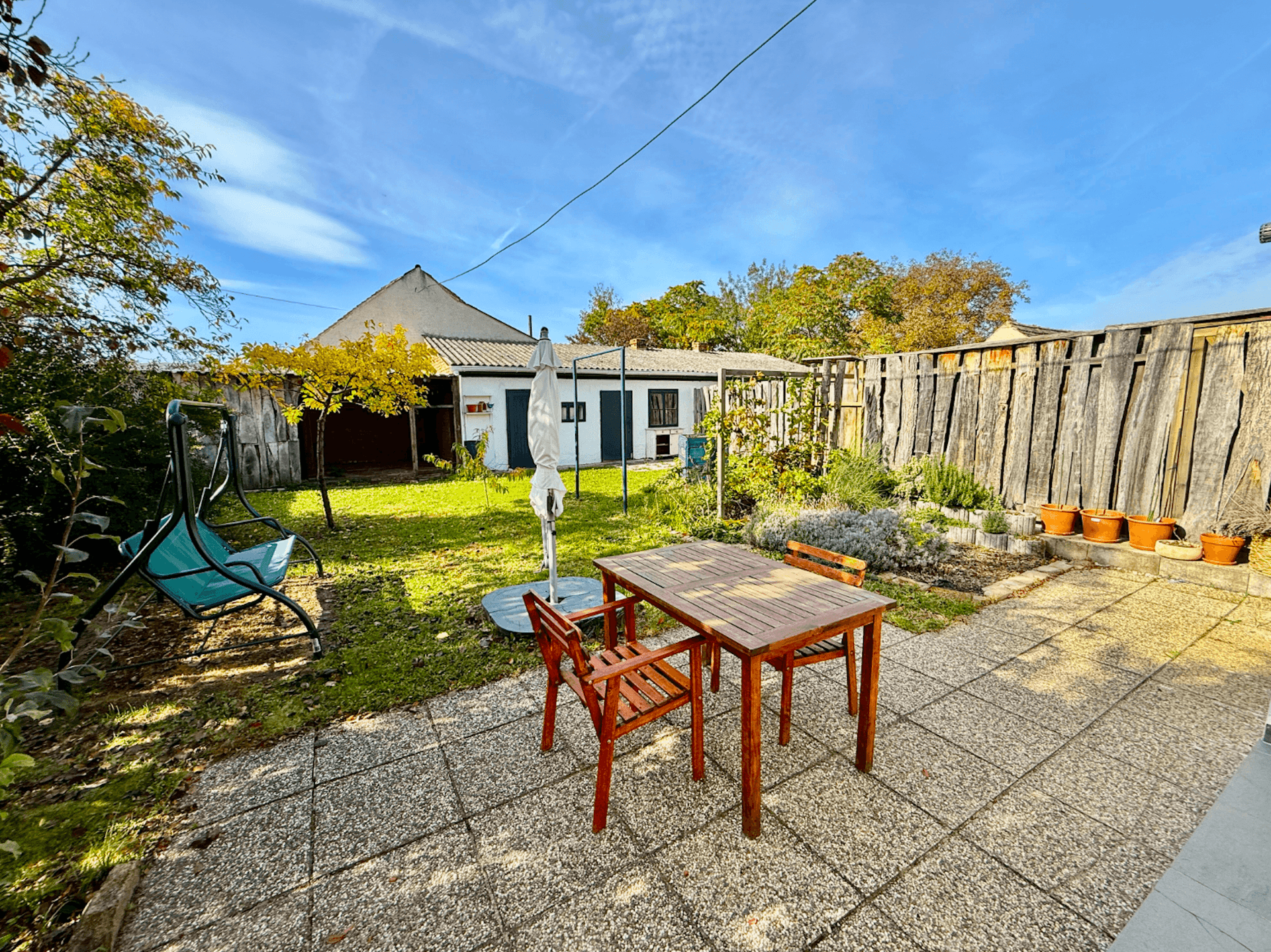 Weitläufiger Garten mit gepflasterter Terrasse, Sitzgelegenheiten und viel Grün.