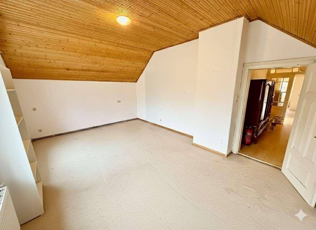 Leerer Raum im Dachgeschoss mit Holzdecke und Teppichboden.
