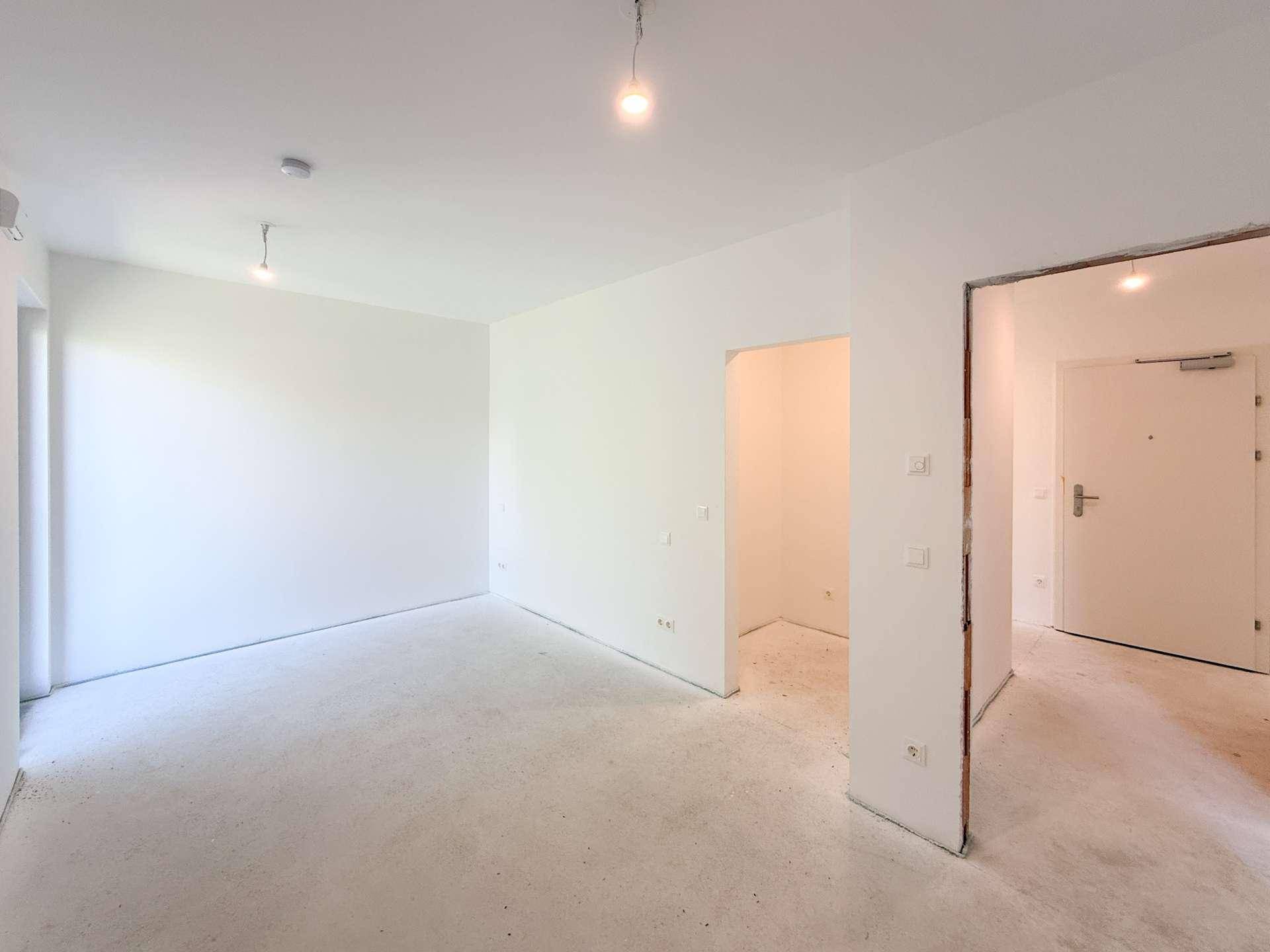 Geräumiges, unmöbliertes Zimmer im Rohbau mit hellem Eingangsbereich und viel Potenzial.