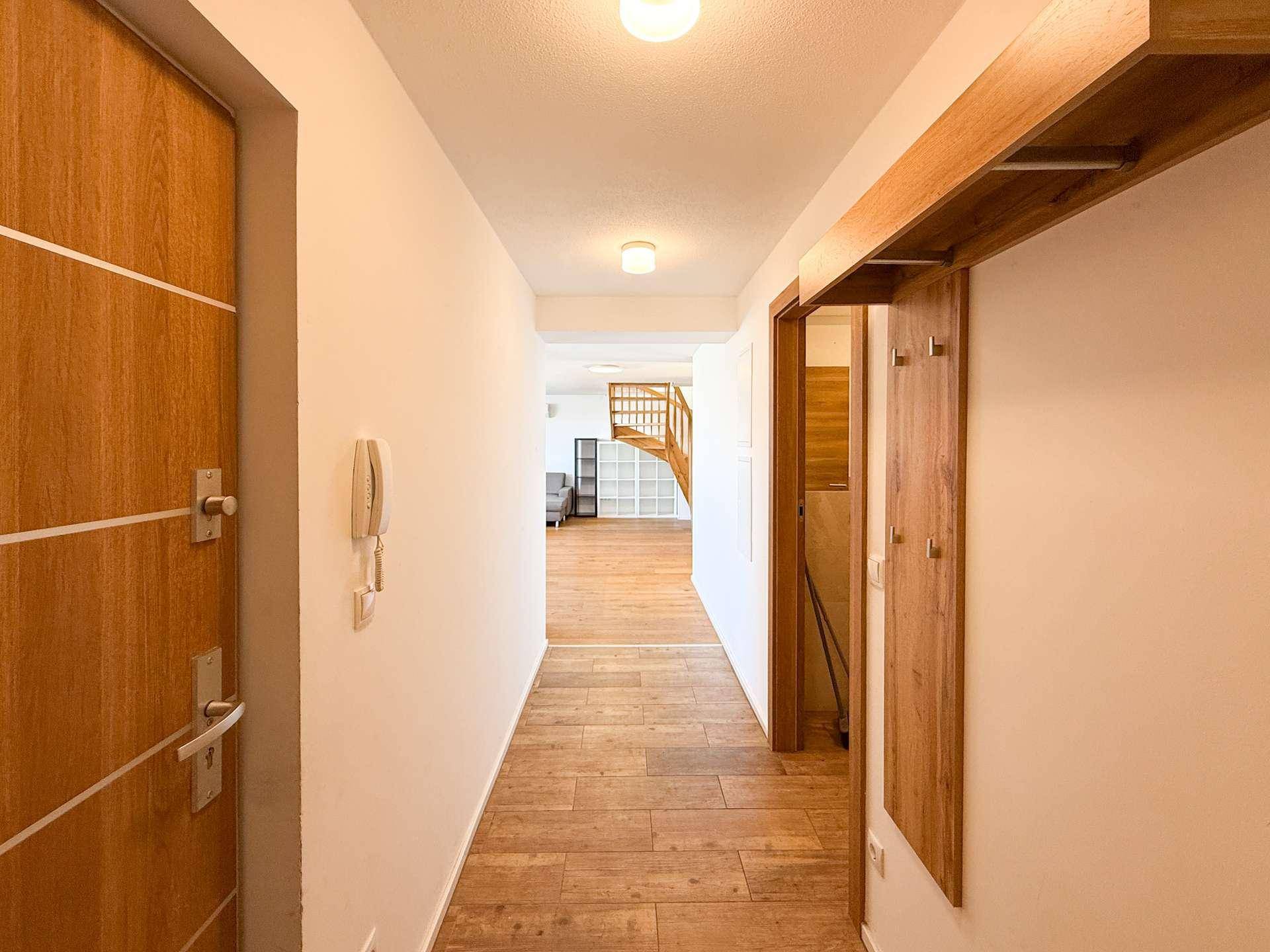 Heller Flur mit Holztüren und passendem Holzboden, der zum offenen Wohnbereich und zur Treppe führt.