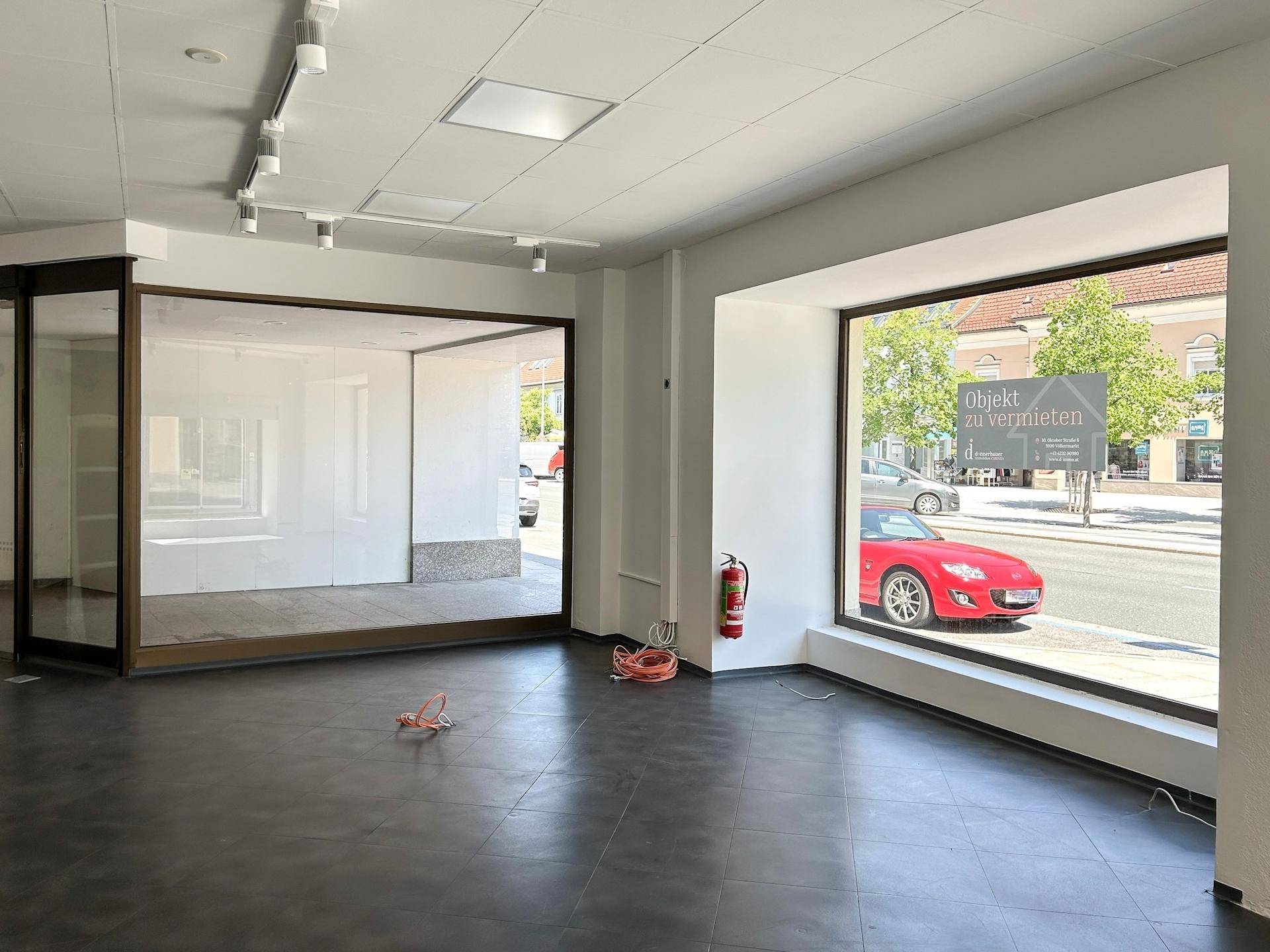 Heller Gewerberaum mit großem Schaufenster und einer eleganten Glasabtrennung, Blick auf die Straße.