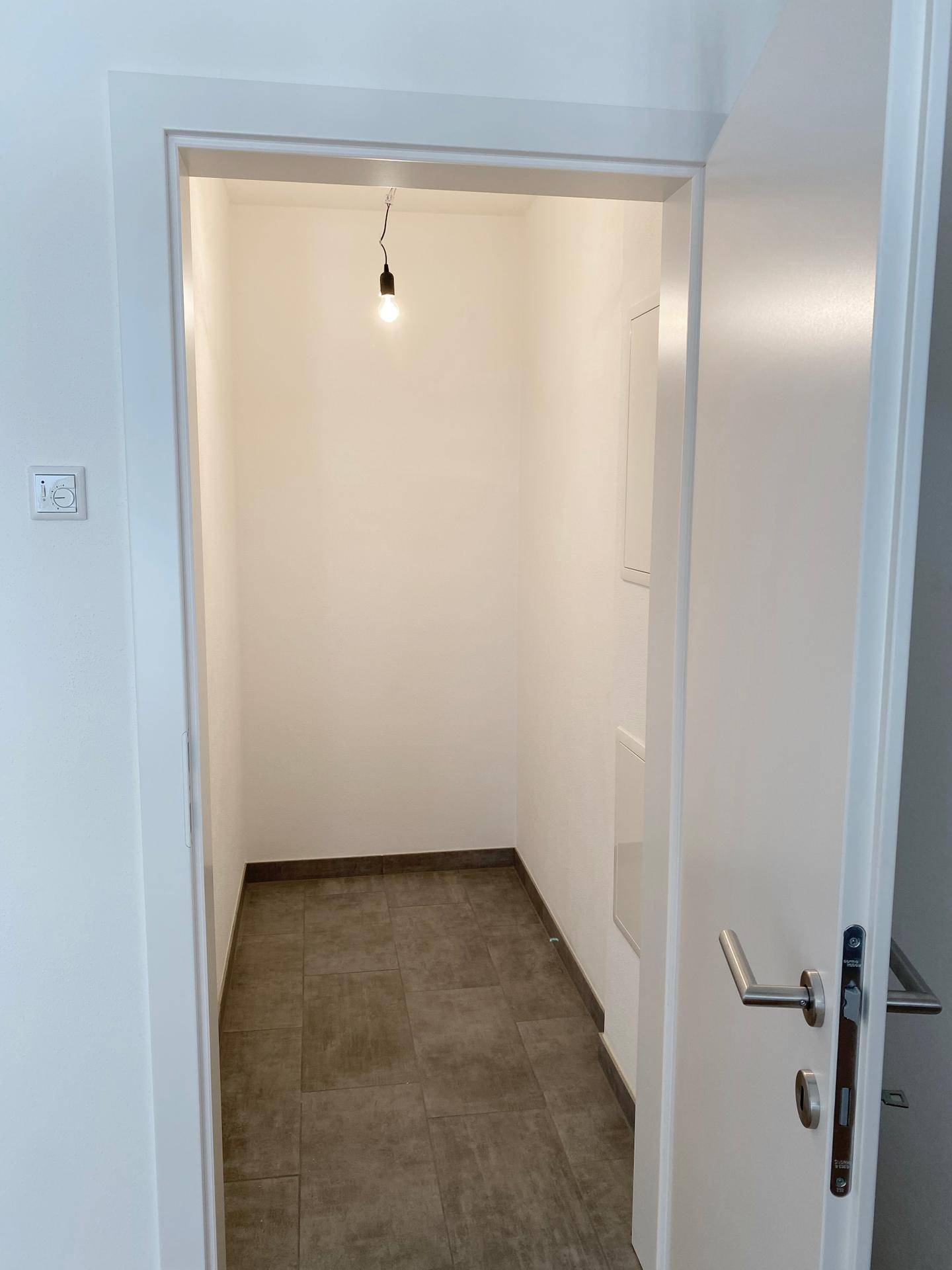 Praktischer Abstellraum mit Fliesenboden und Anschlussmöglichkeiten für Haushaltsgeräte.