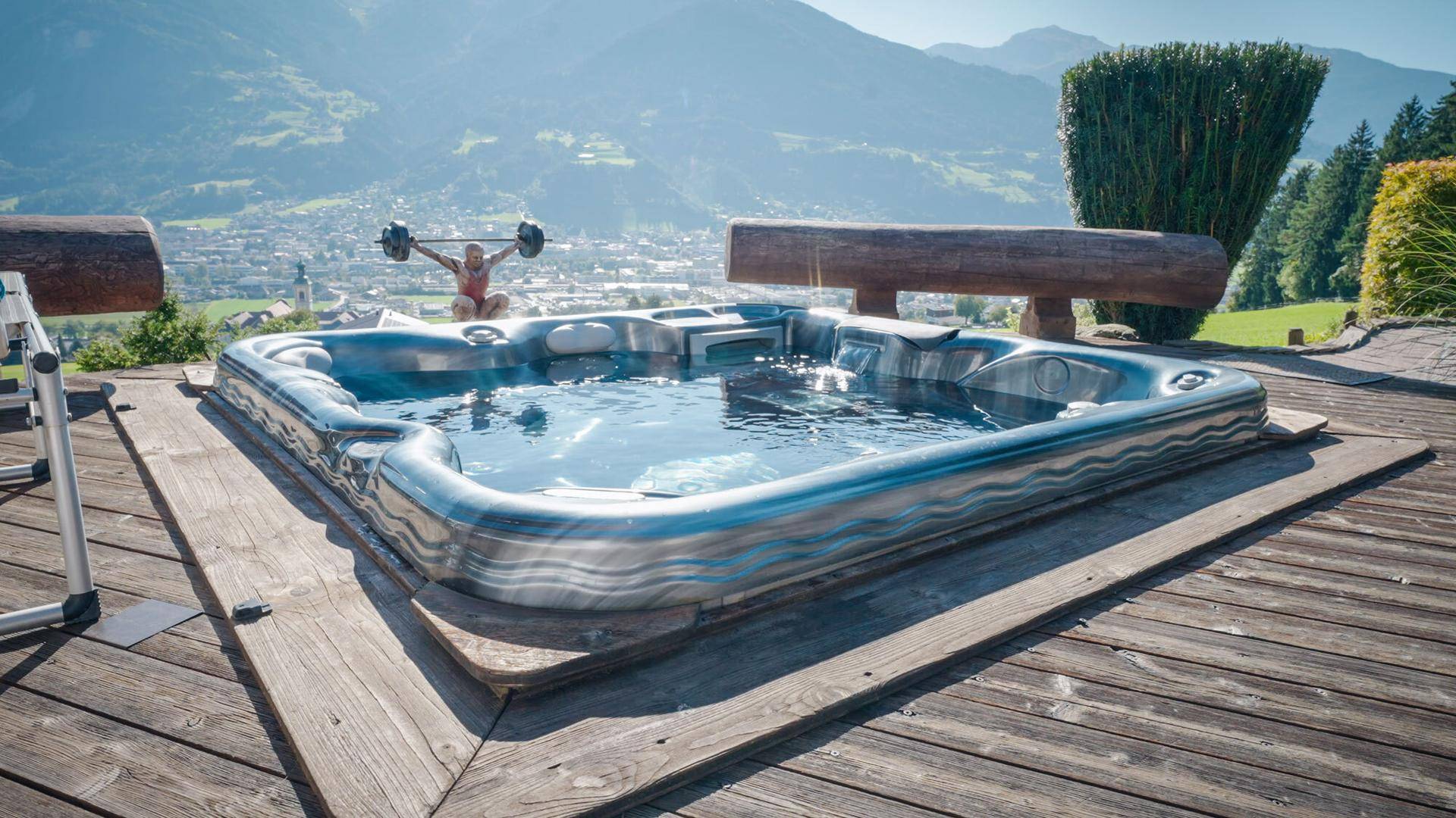 Whirlpool auf einer Holzterrasse mit Panoramablick auf das Tal und die Berge.