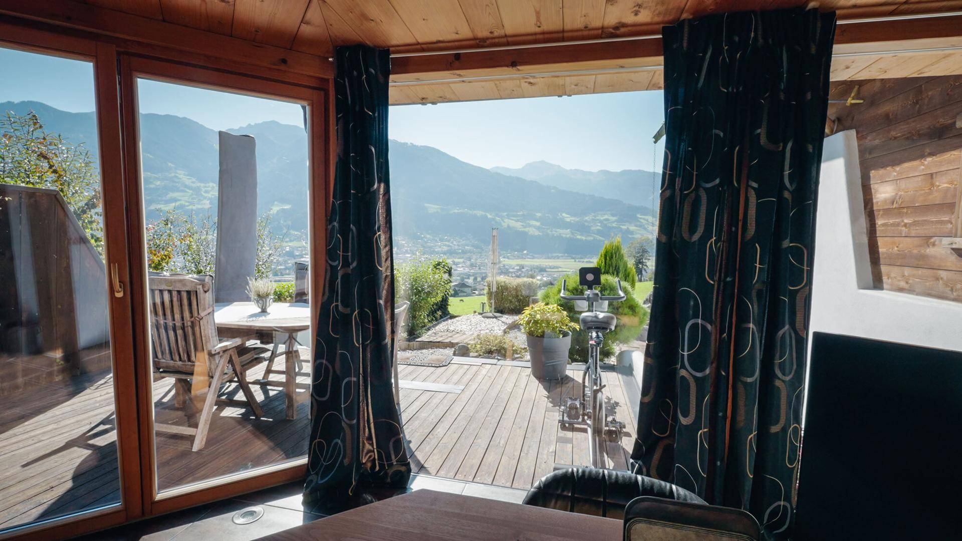 Heller Raum mit Zugang zur Holzterrasse und weitem Blick auf die Berge.
