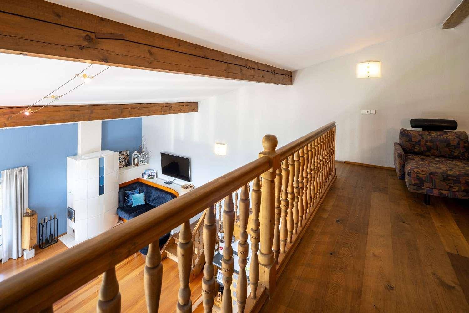 Galerie mit Holzgeländer, die den Blick auf den hellen Wohnbereich freigibt.