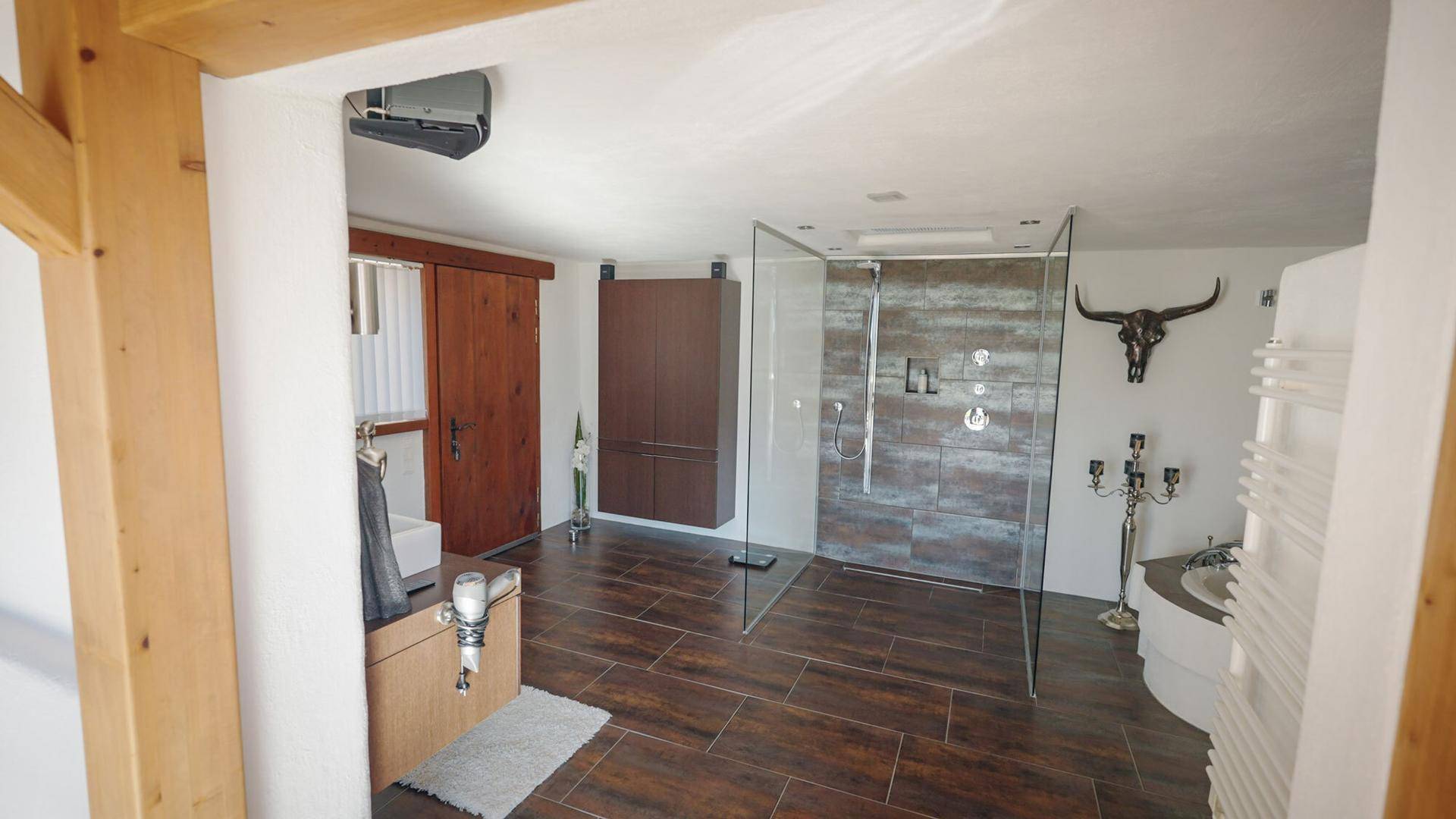 Modernes Badezimmer mit begehbarer Dusche, dunklen Fliesen und rustikalen Holzakzenten.