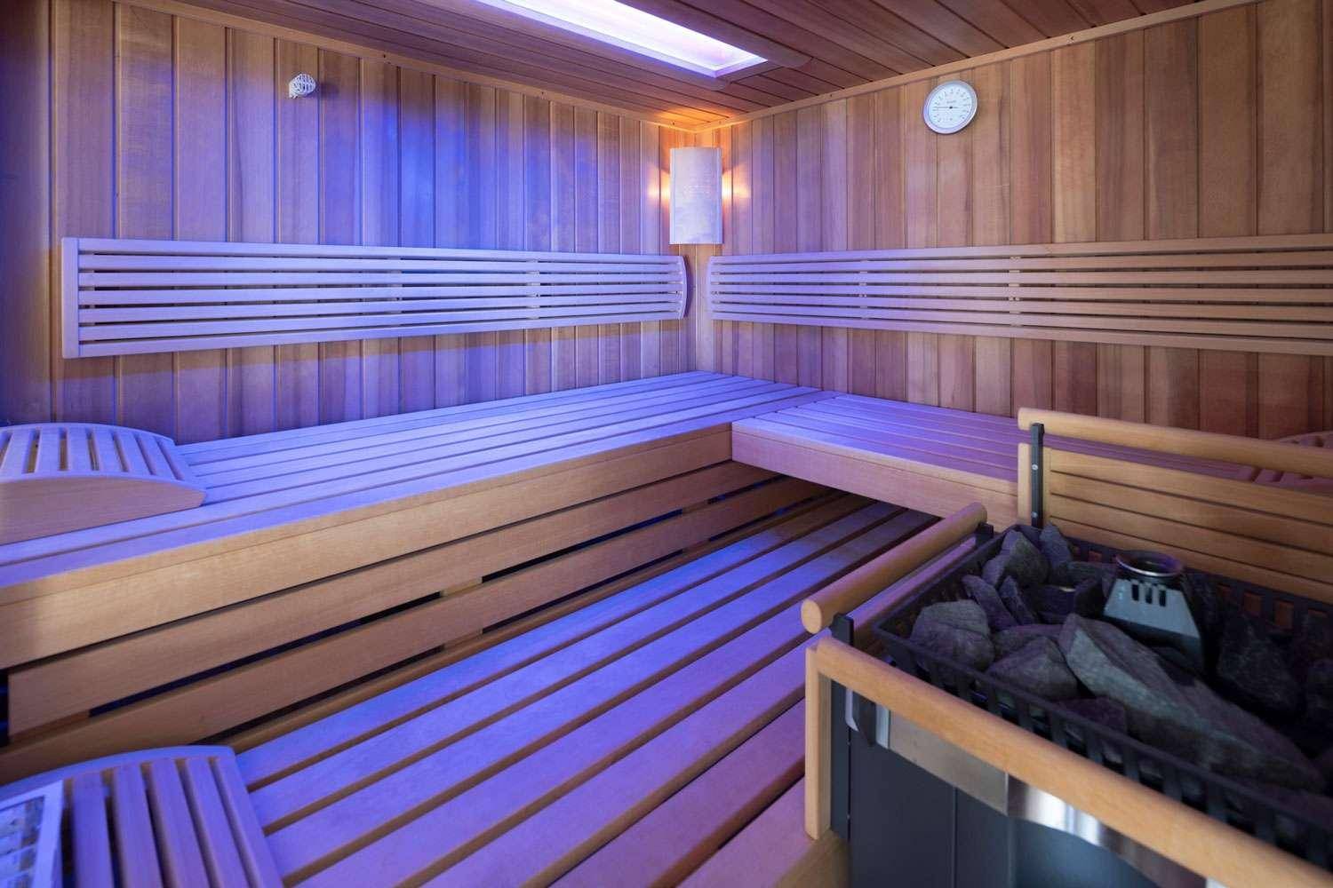 Gemütliche Holzsauna mit Sitzbänken und stimmungsvoller Beleuchtung für Entspannung.
